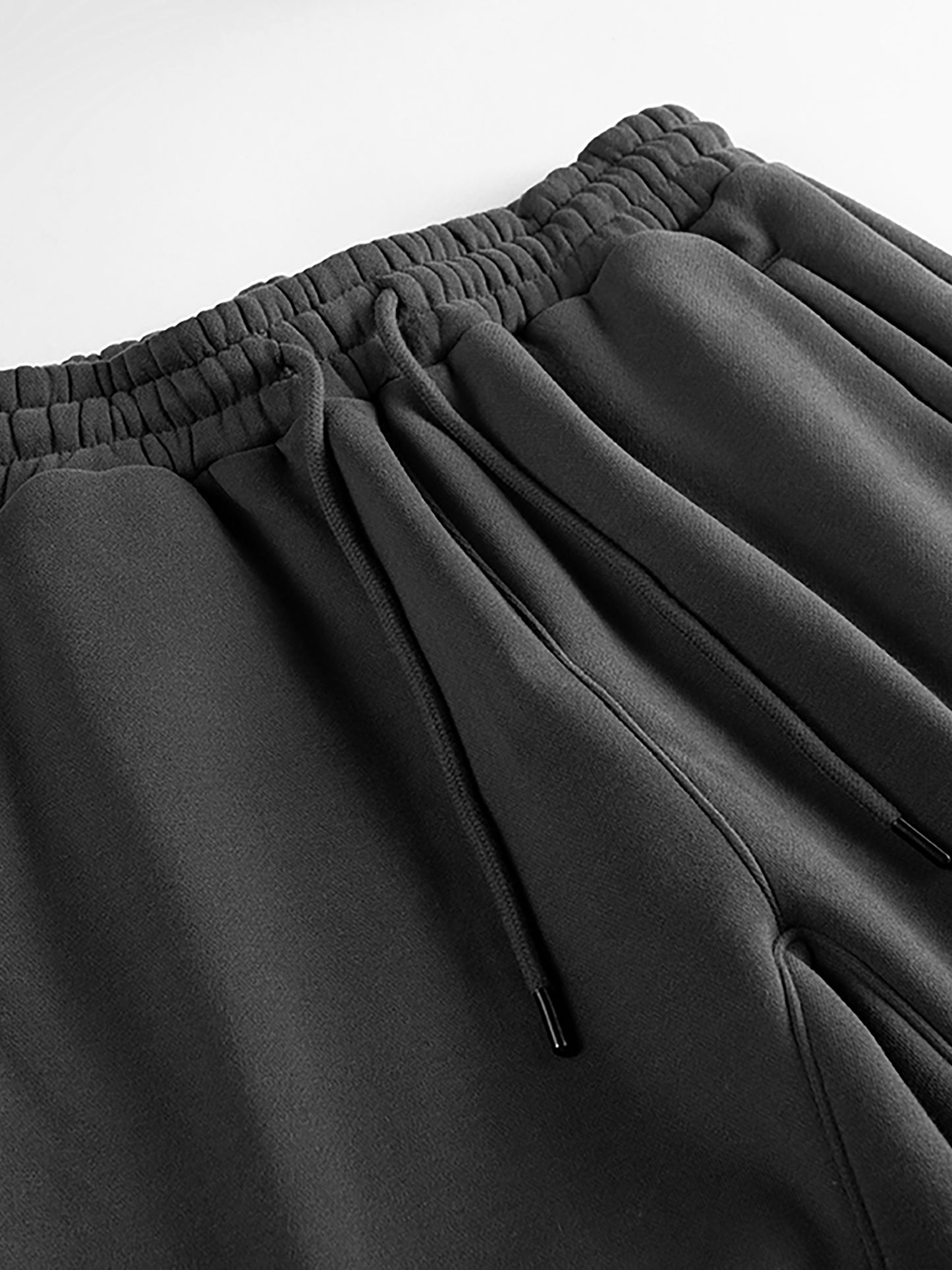 Close-up of dark gray pants with an elastic waistband on a light gray background