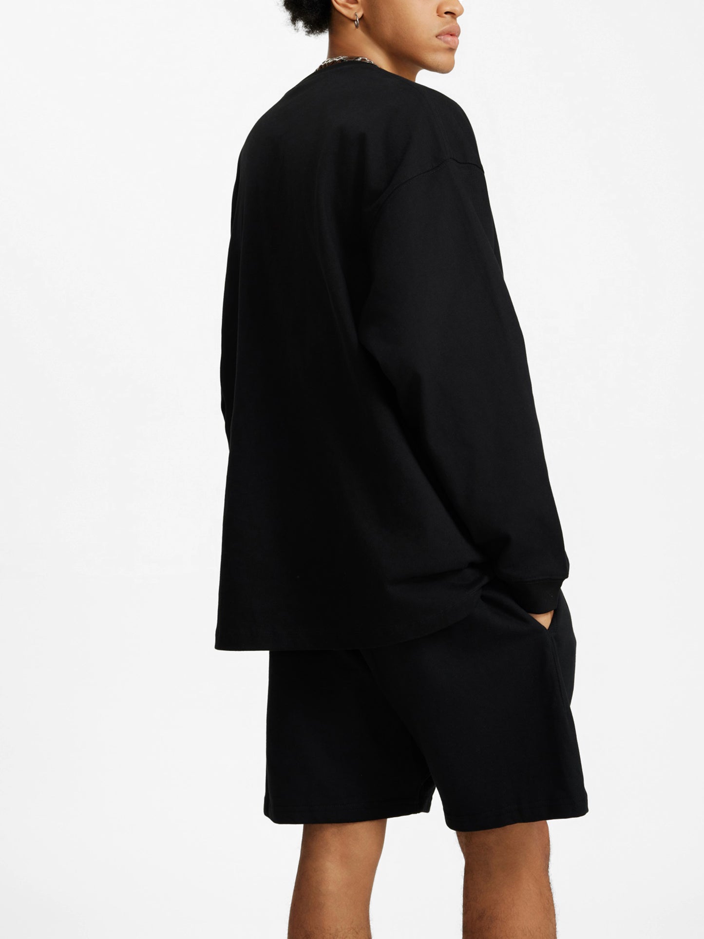 Person wearing a black oversized sweatshirt and shorts on a white background.