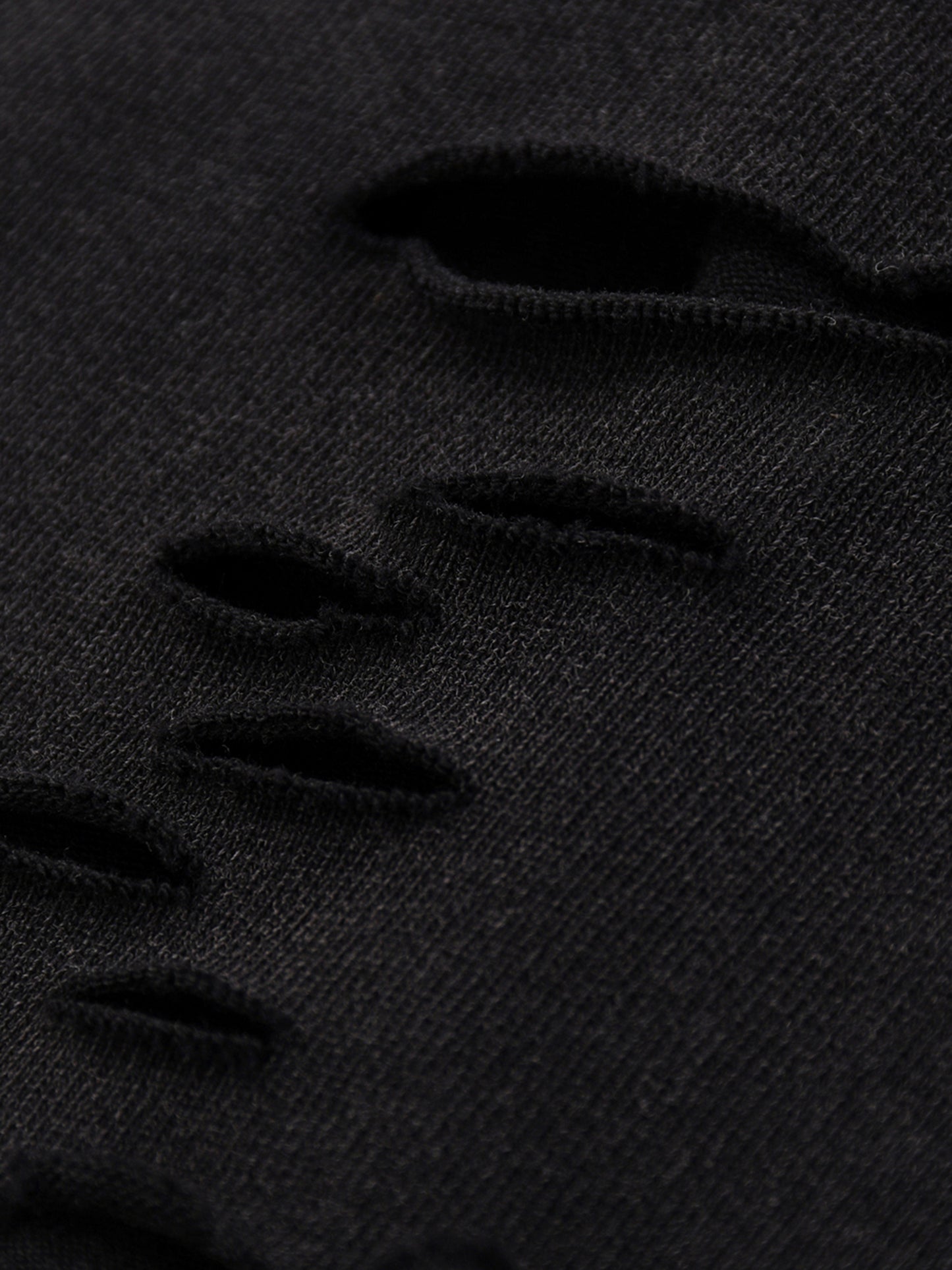 Close-up of black distressed denim fabric