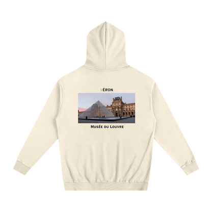 Beige hoodie with a graphic of the Louvre Museum on the back