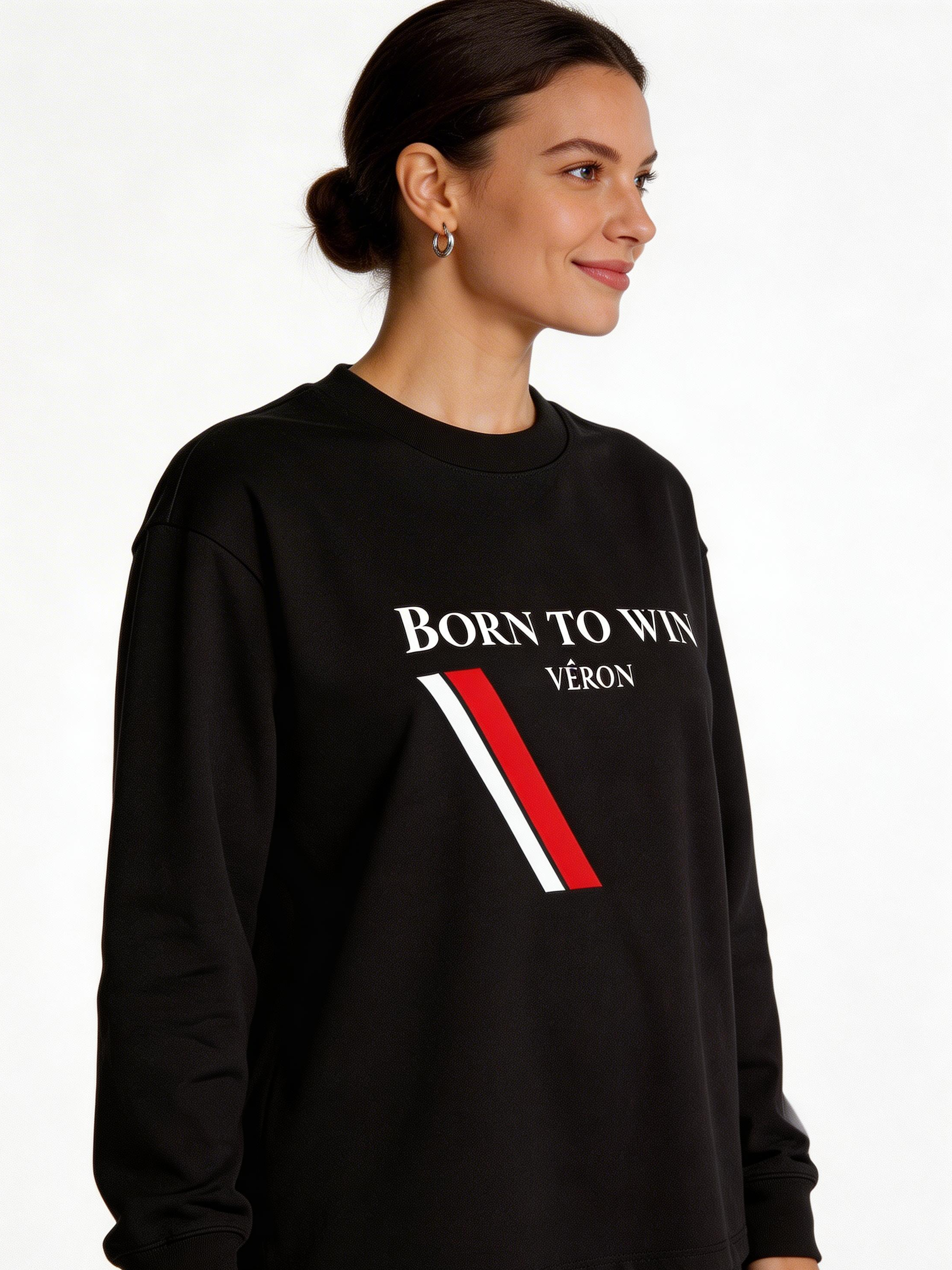 Woman wearing a black sweatshirt with 'Born to Win VÉRON' text on a white background