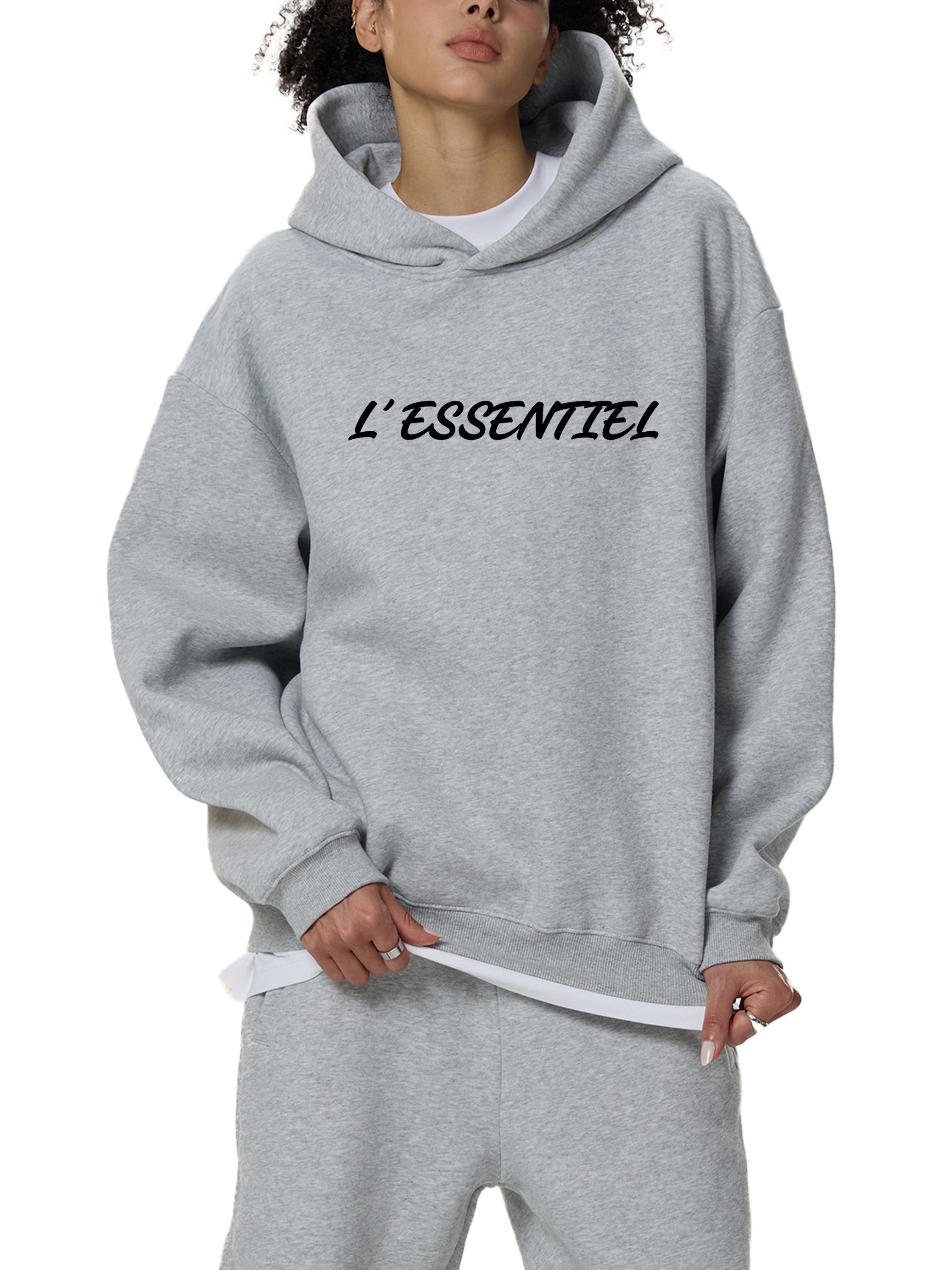 Person wearing a gray hoodie with 'L'ESSENTIEL' text on a white background