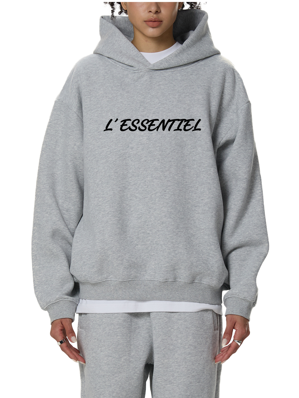 Person wearing a gray hoodie with 'L'Essentiel' text on a white background