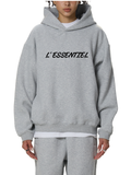 Person wearing a gray hoodie with 'L'Essentiel' text on a white background