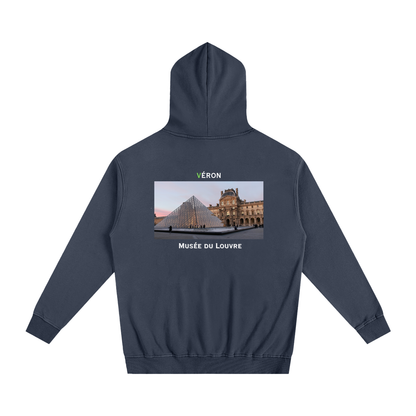 Navy blue hoodie with a graphic of the Louvre Museum on the back, displayed on a white background.