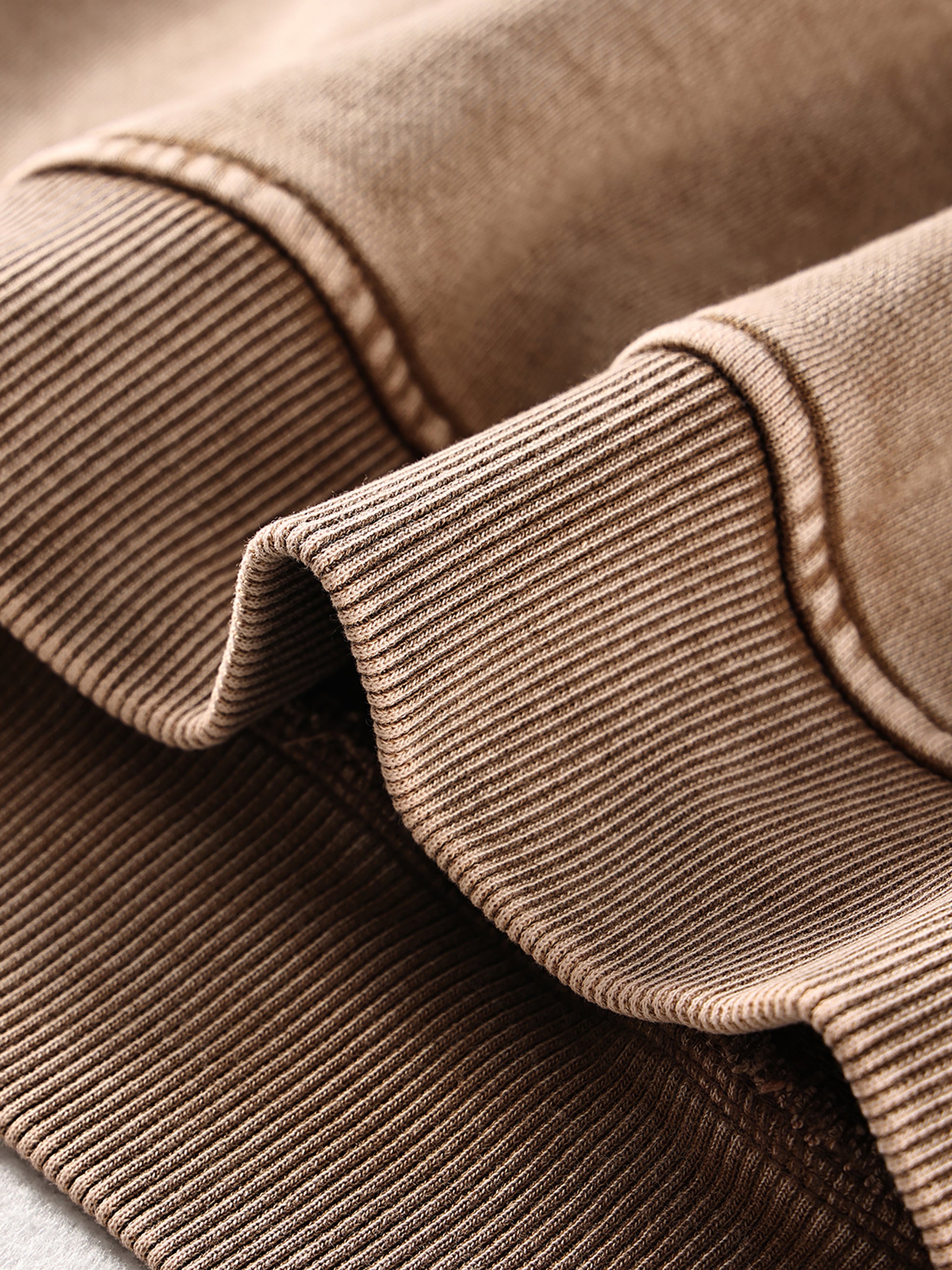 Close-up of brown corduroy fabric with a focus on texture and stitching.