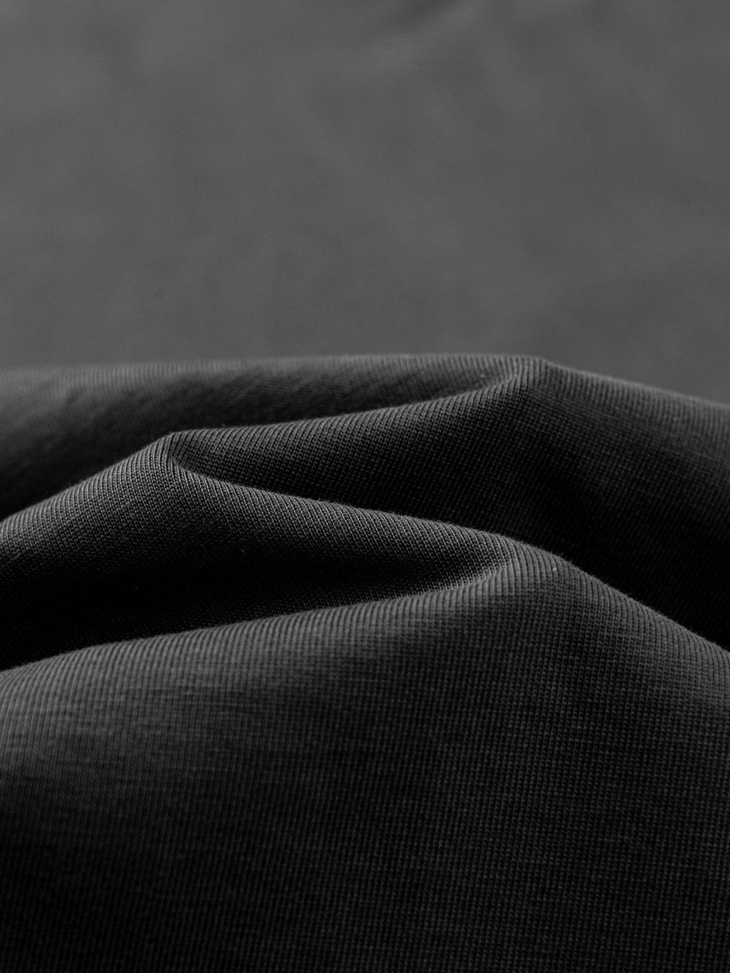 Close-up of dark gray fabric with folds on a matching background