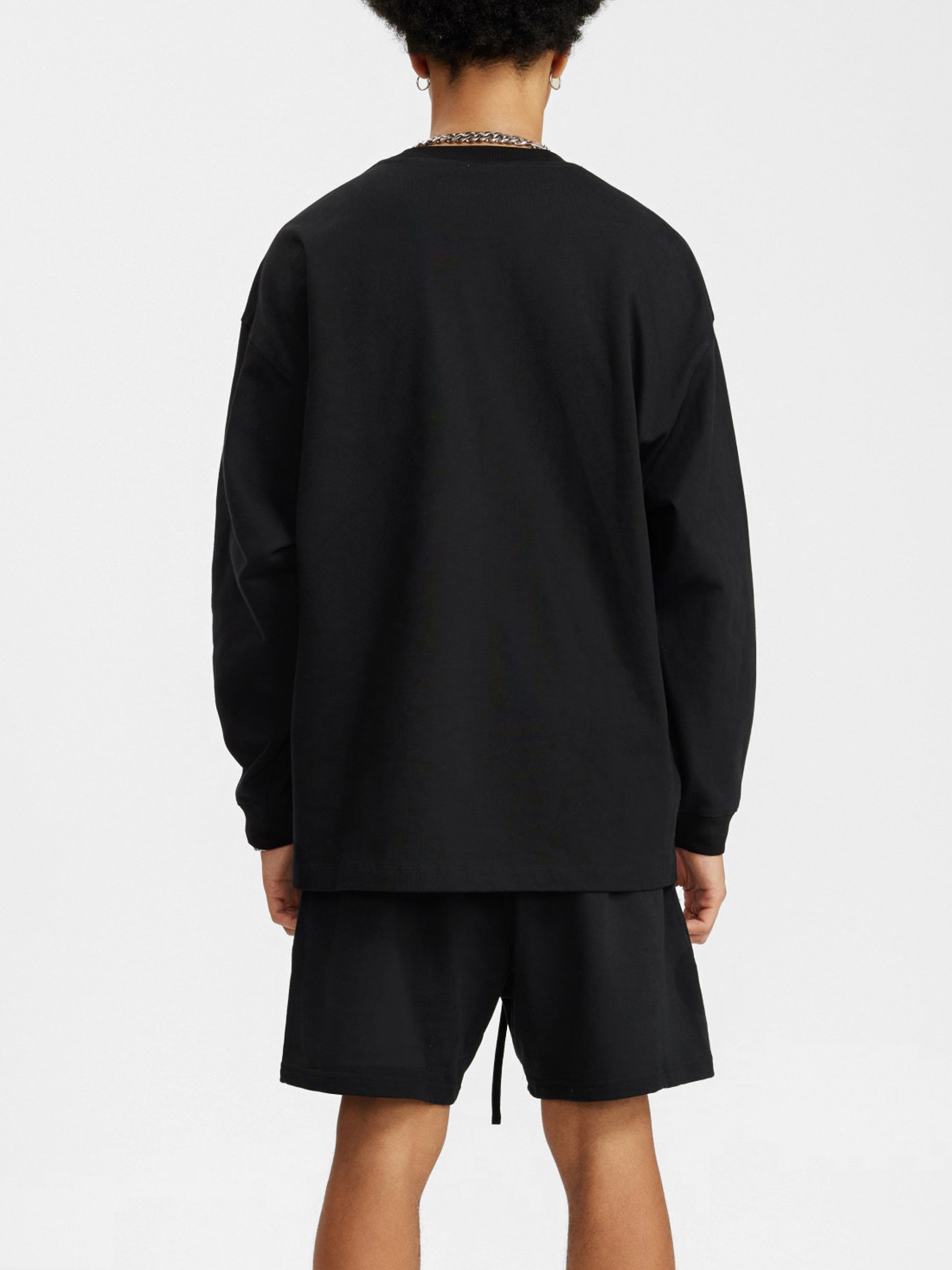 Person wearing a black sweatshirt and shorts set on a white background