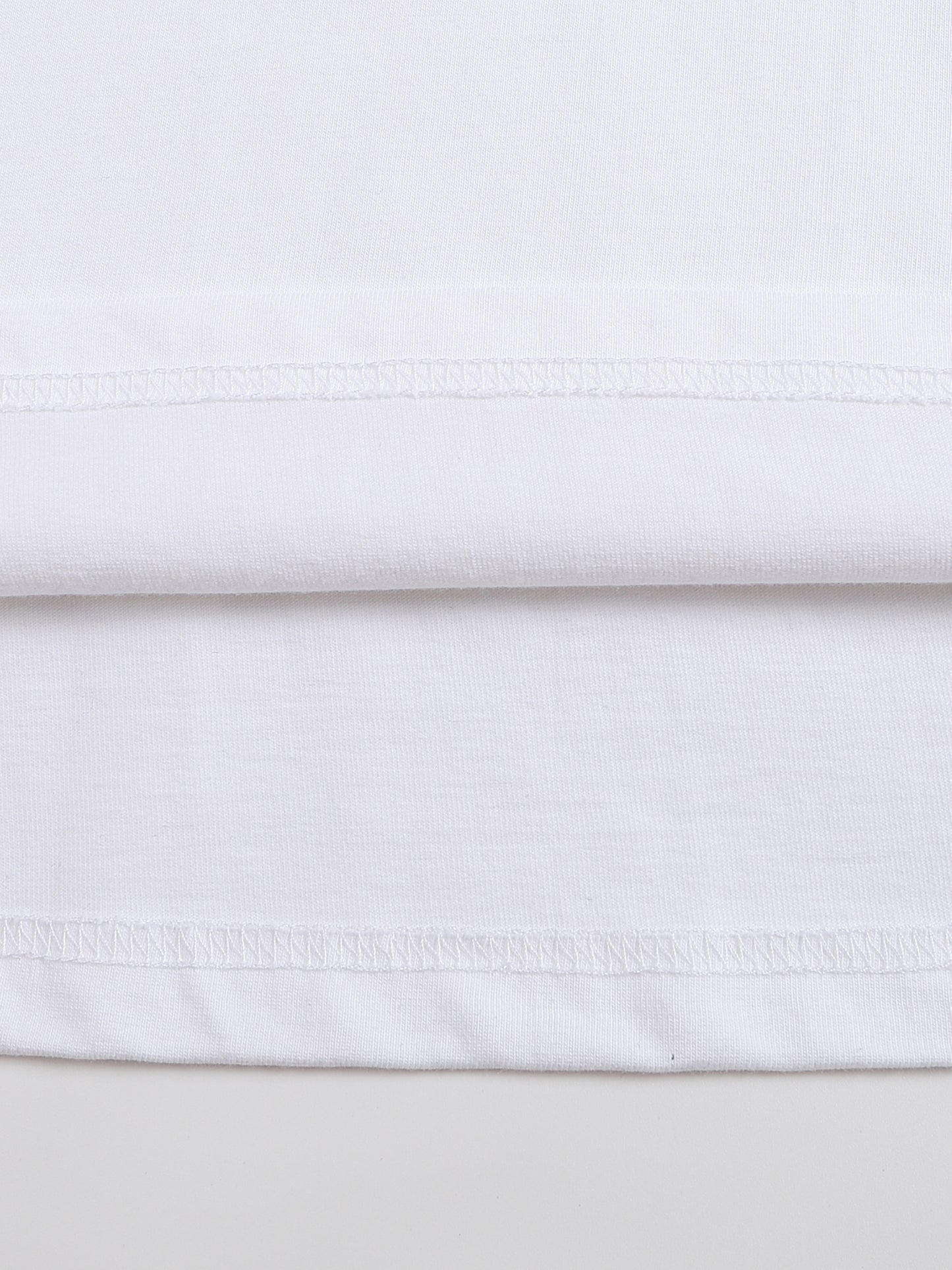 Close-up of white fabric with a subtle pattern on a light gray background