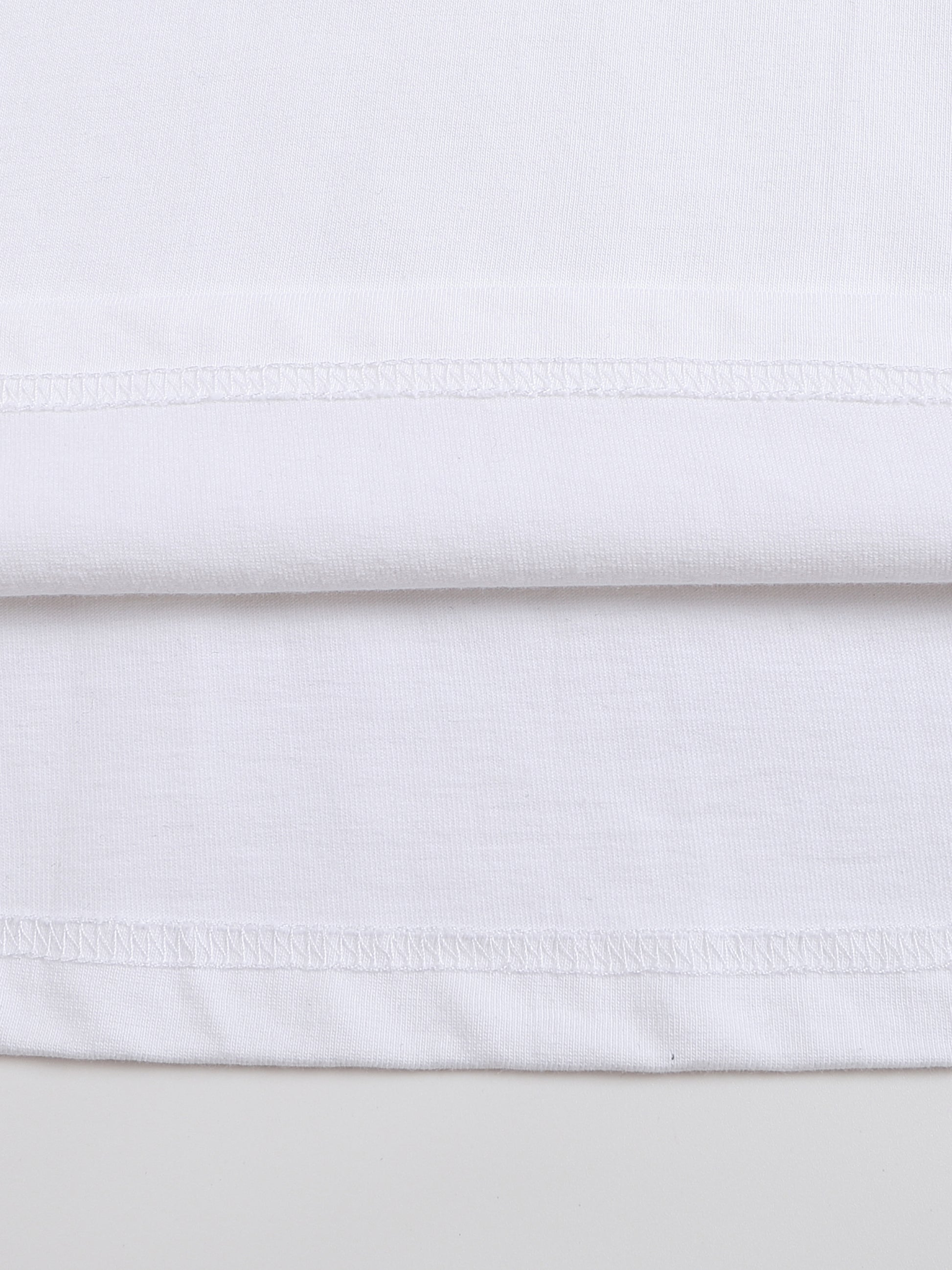 Close-up of white fabric with a subtle pattern on a light gray background