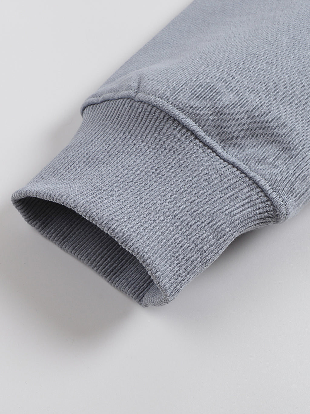 Close-up of a gray sweater sleeve on a light gray background