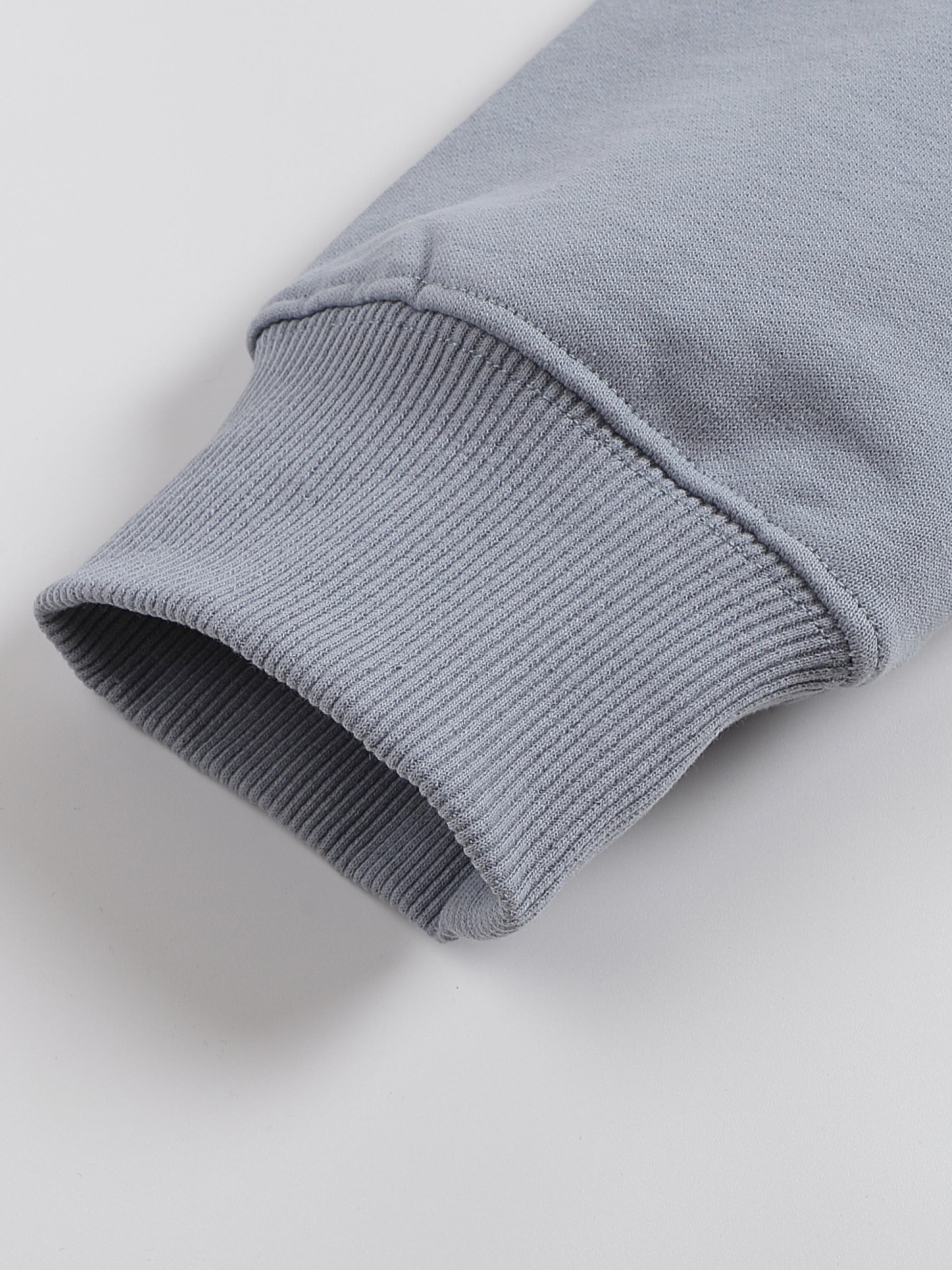 Close-up of a gray sweater sleeve on a light gray background
