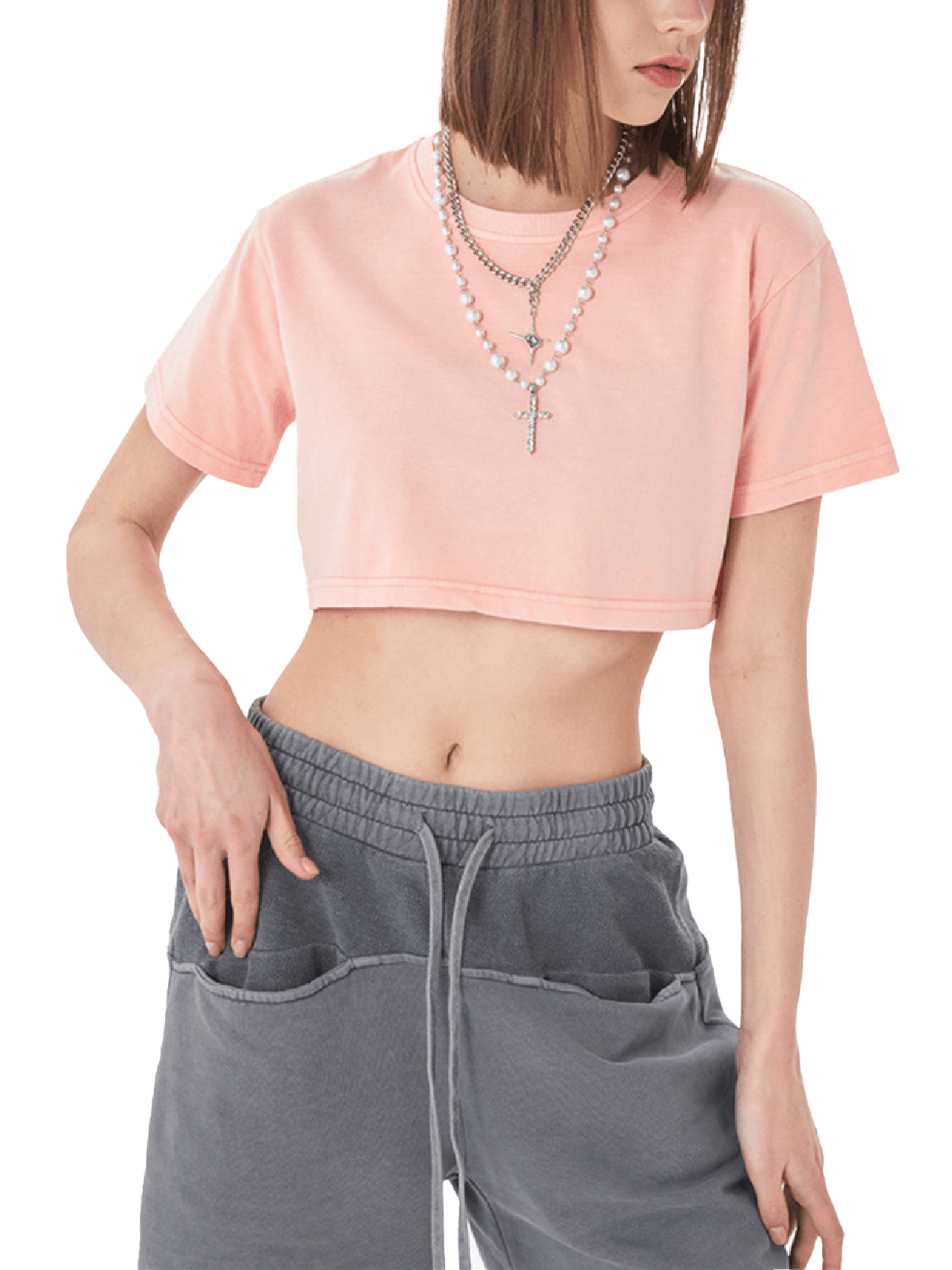 Person wearing a pink cropped t-shirt and gray sweatpants on a white background