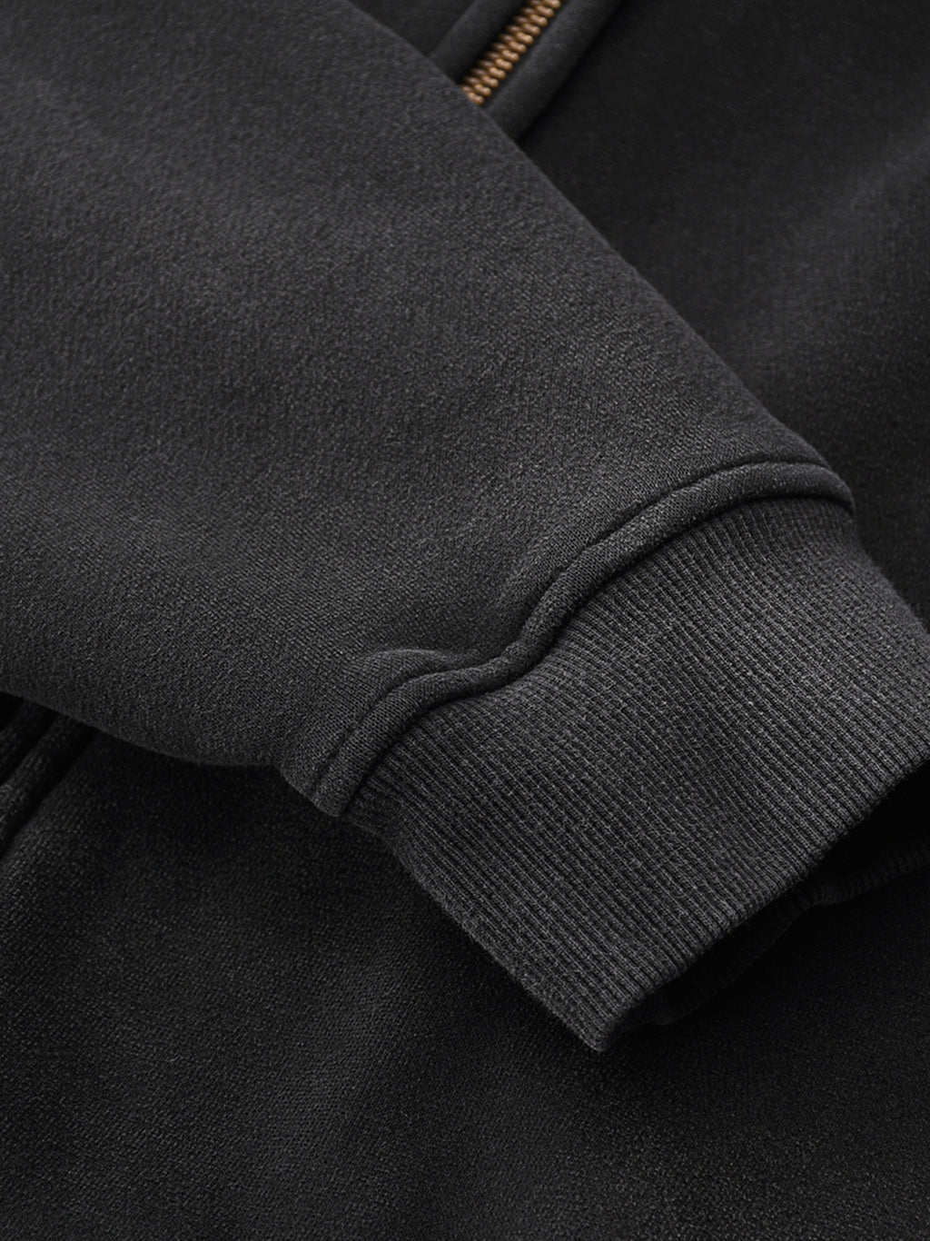 Close-up of a dark gray jacket sleeve with a zipper detail.