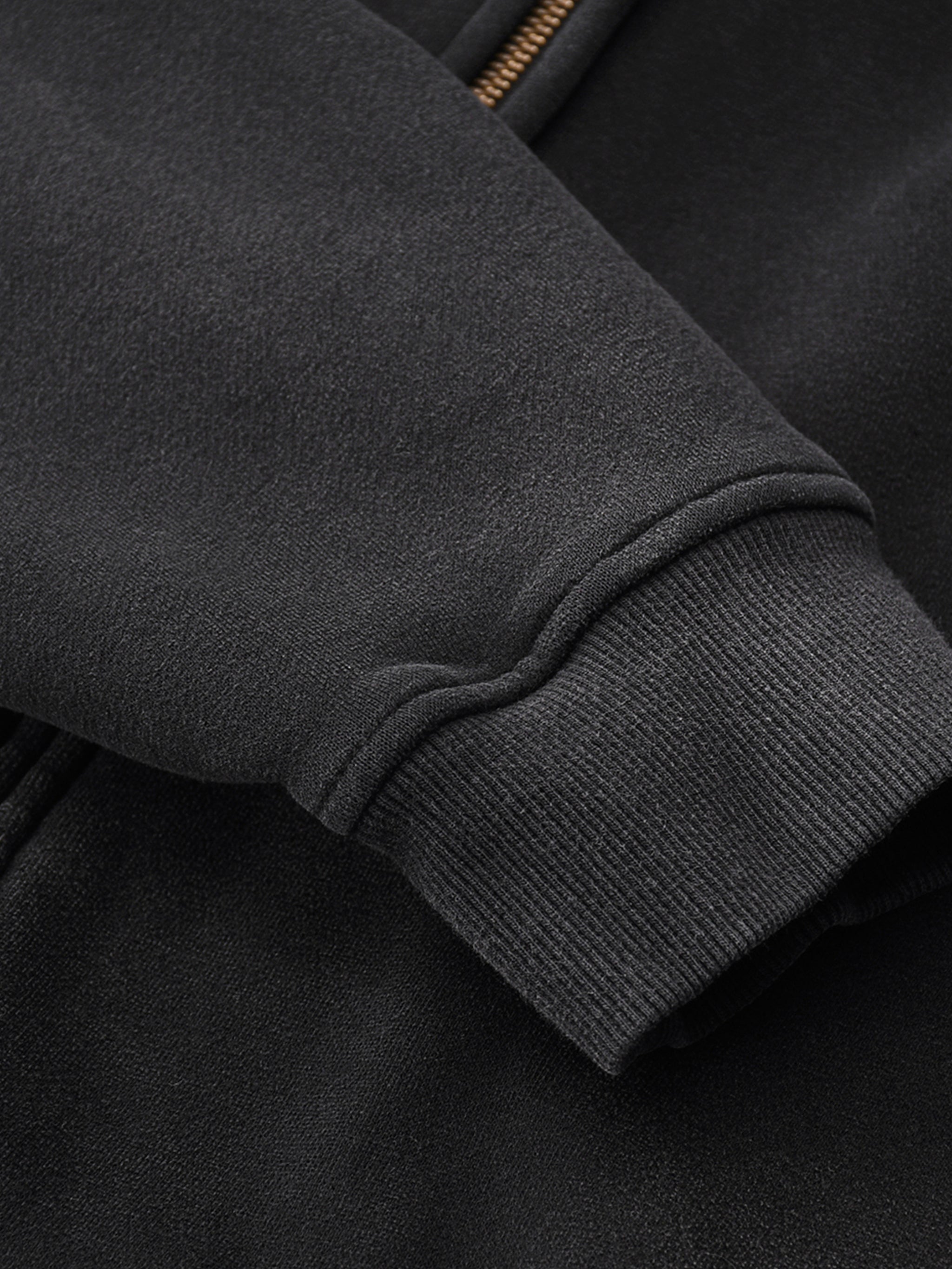 Close-up of a dark gray jacket sleeve with a zipper detail.