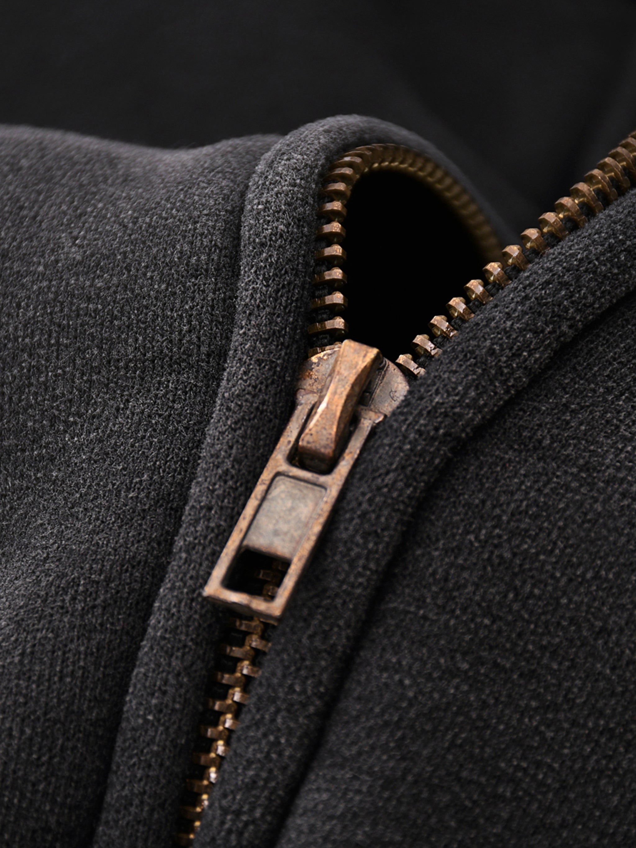 Close-up of a black jacket with a bronze zipper