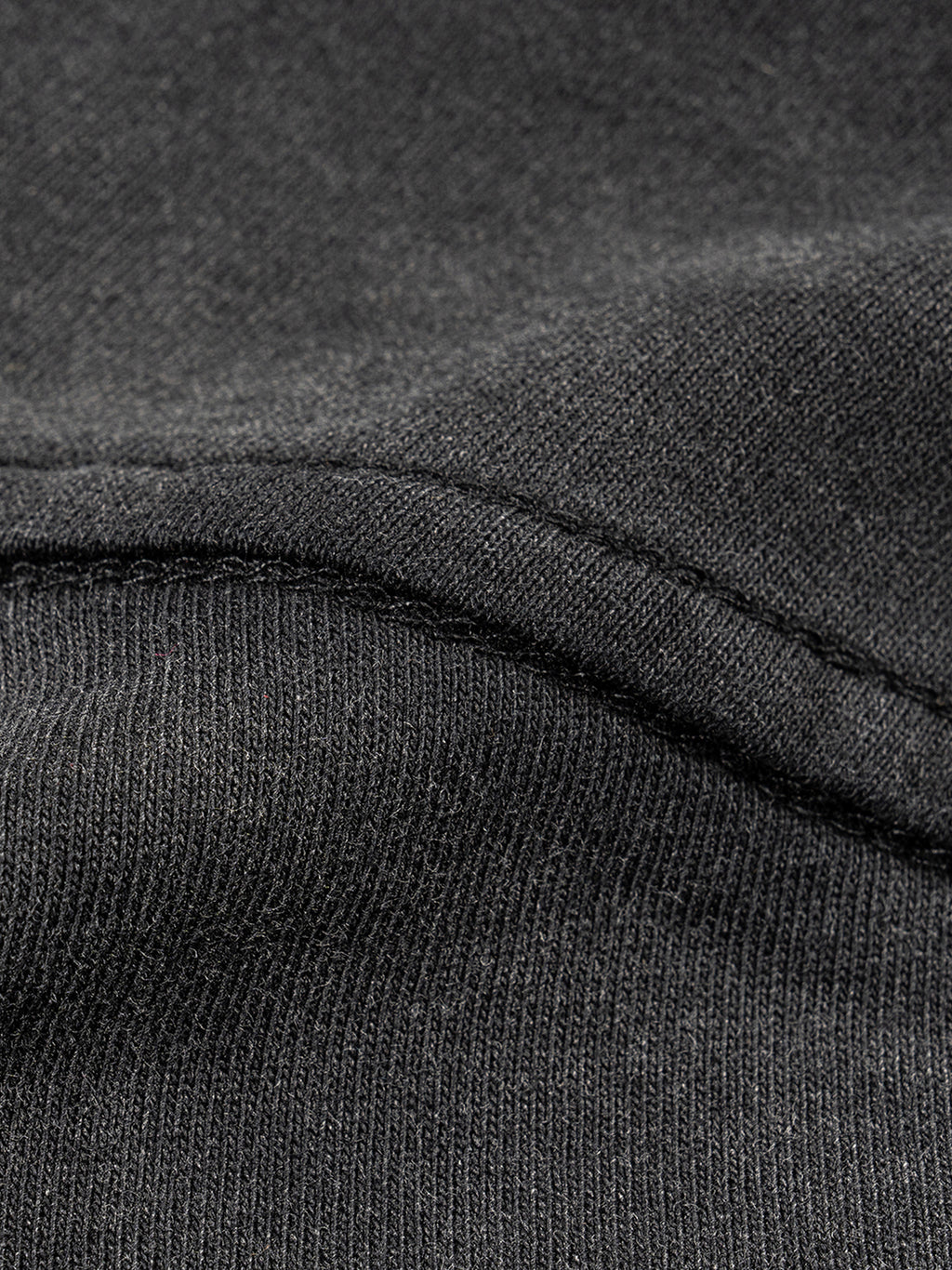 Close-up of dark gray fabric with a focus on texture and stitching.
