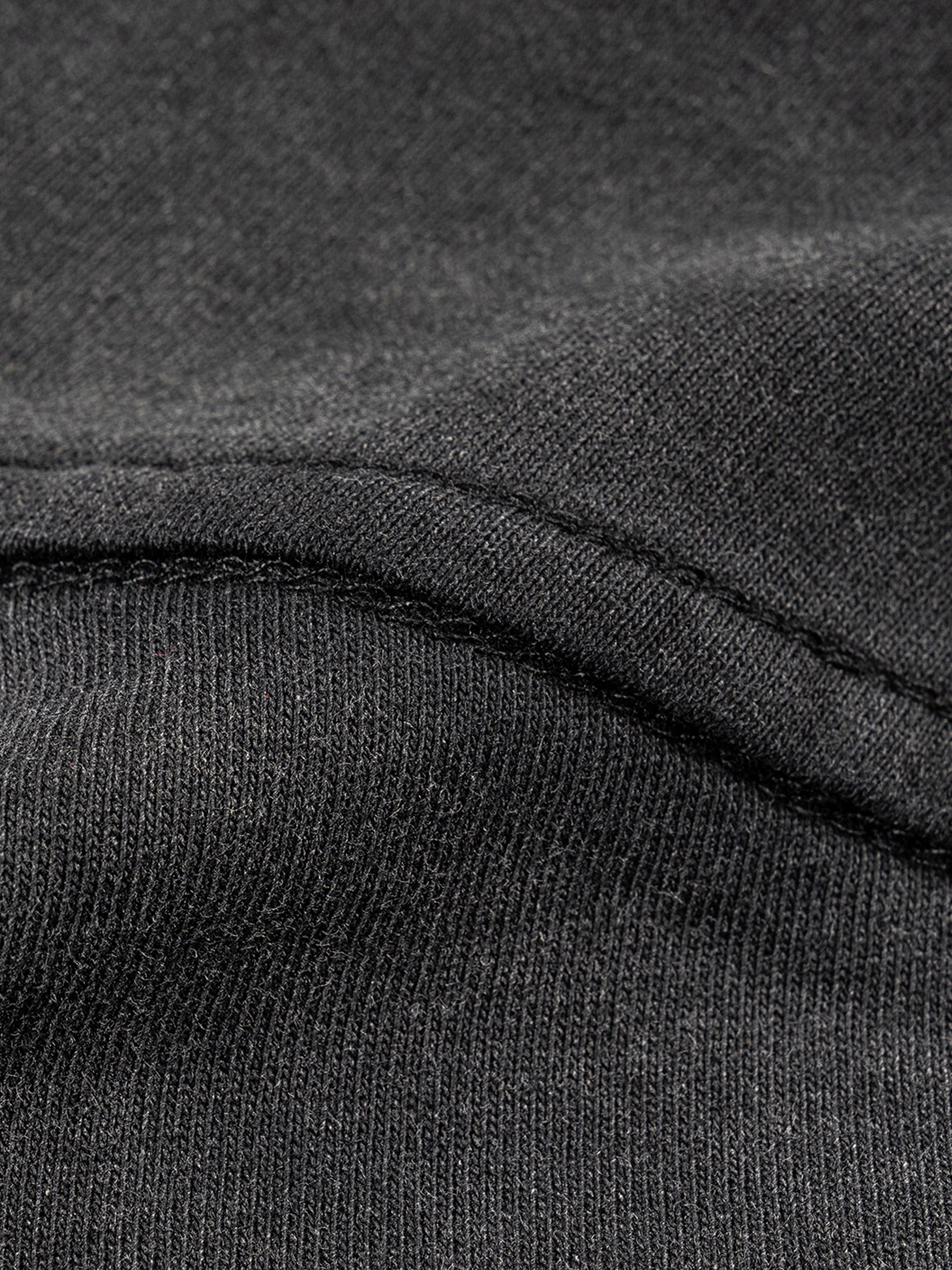 Close-up of dark gray fabric with a focus on texture and stitching.