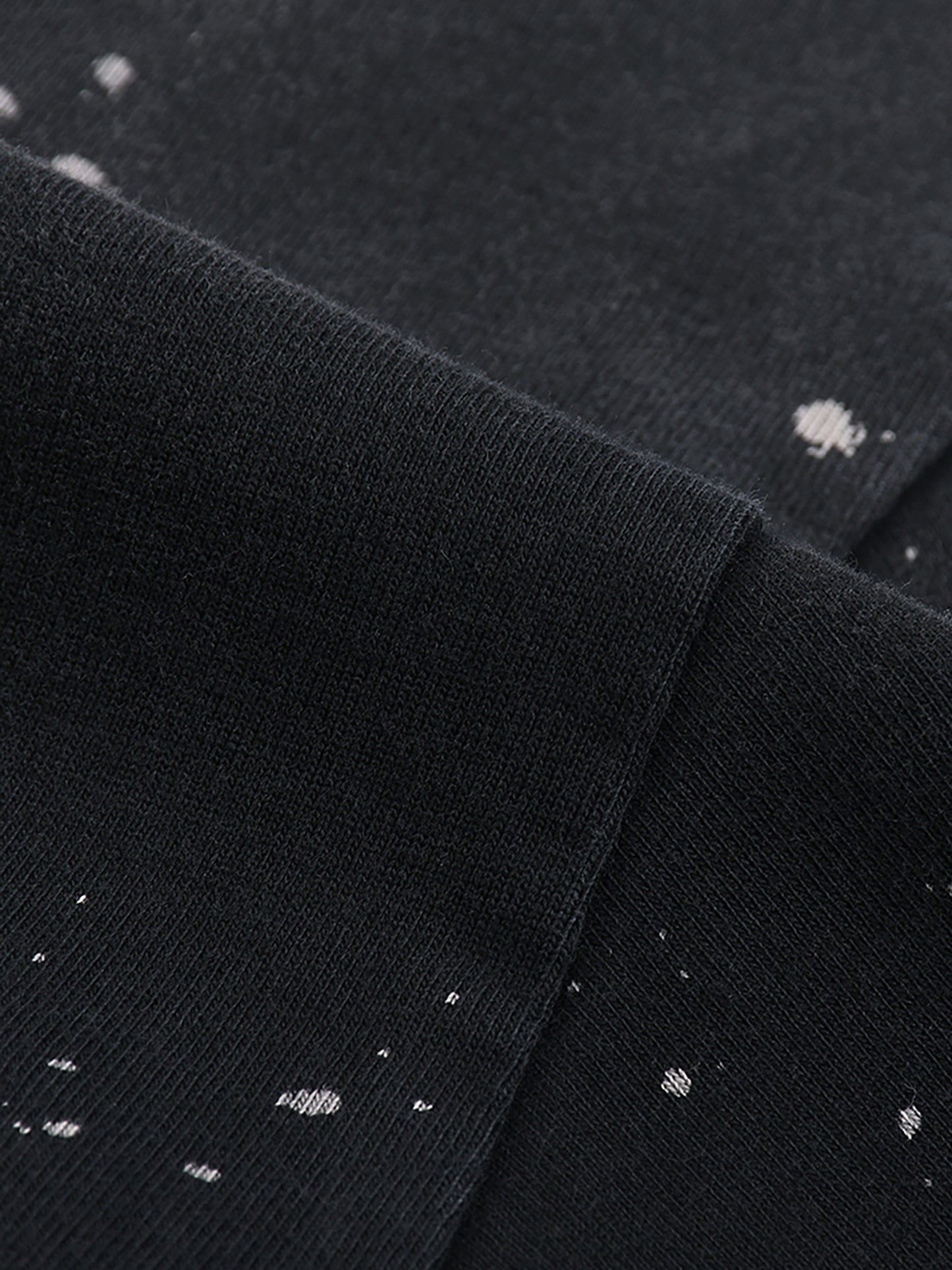 Close-up of black fabric with white speckles, possibly a shirt or sweater.
