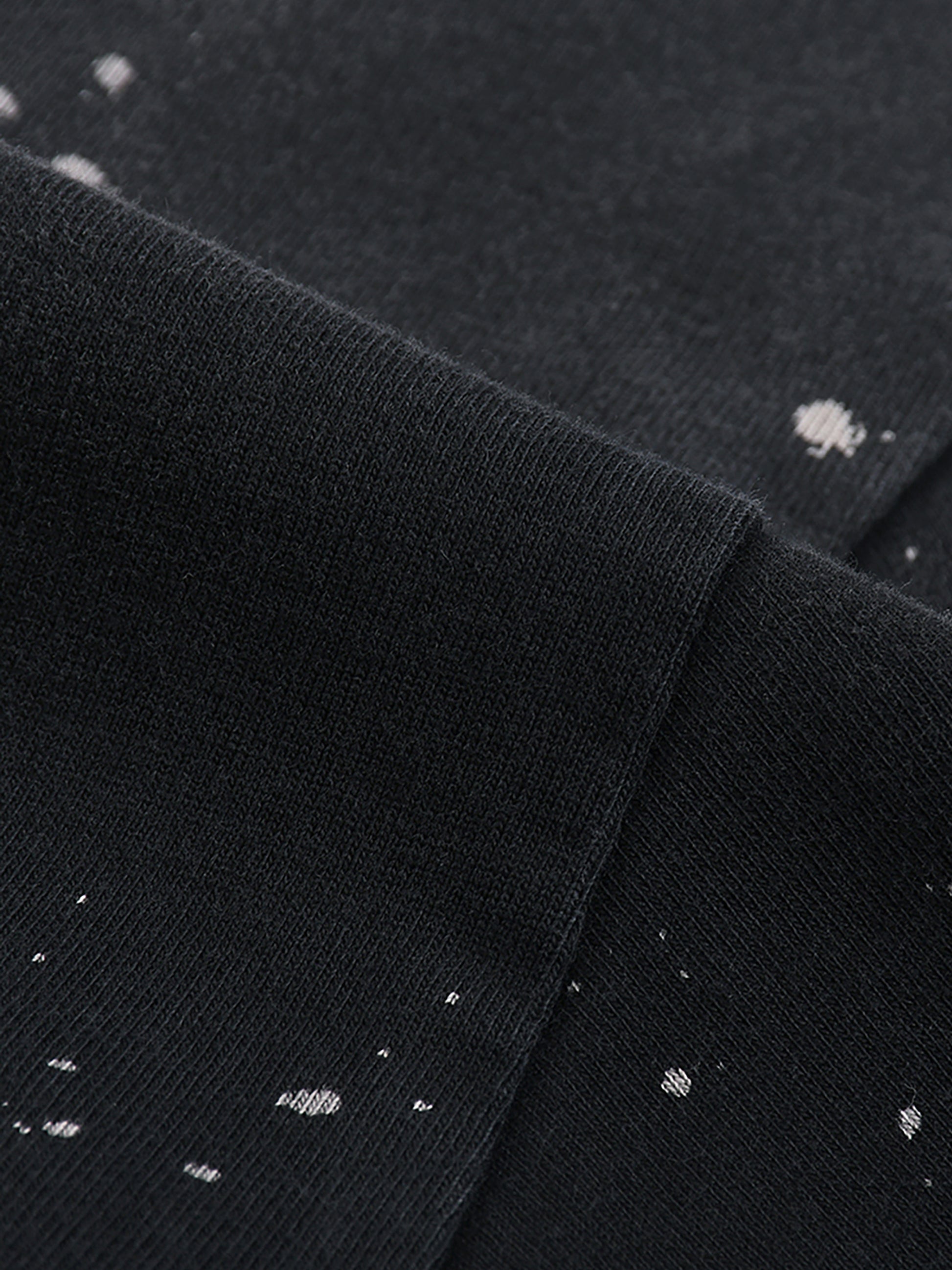 Close-up of black fabric with white speckles, possibly a shirt or sweater.