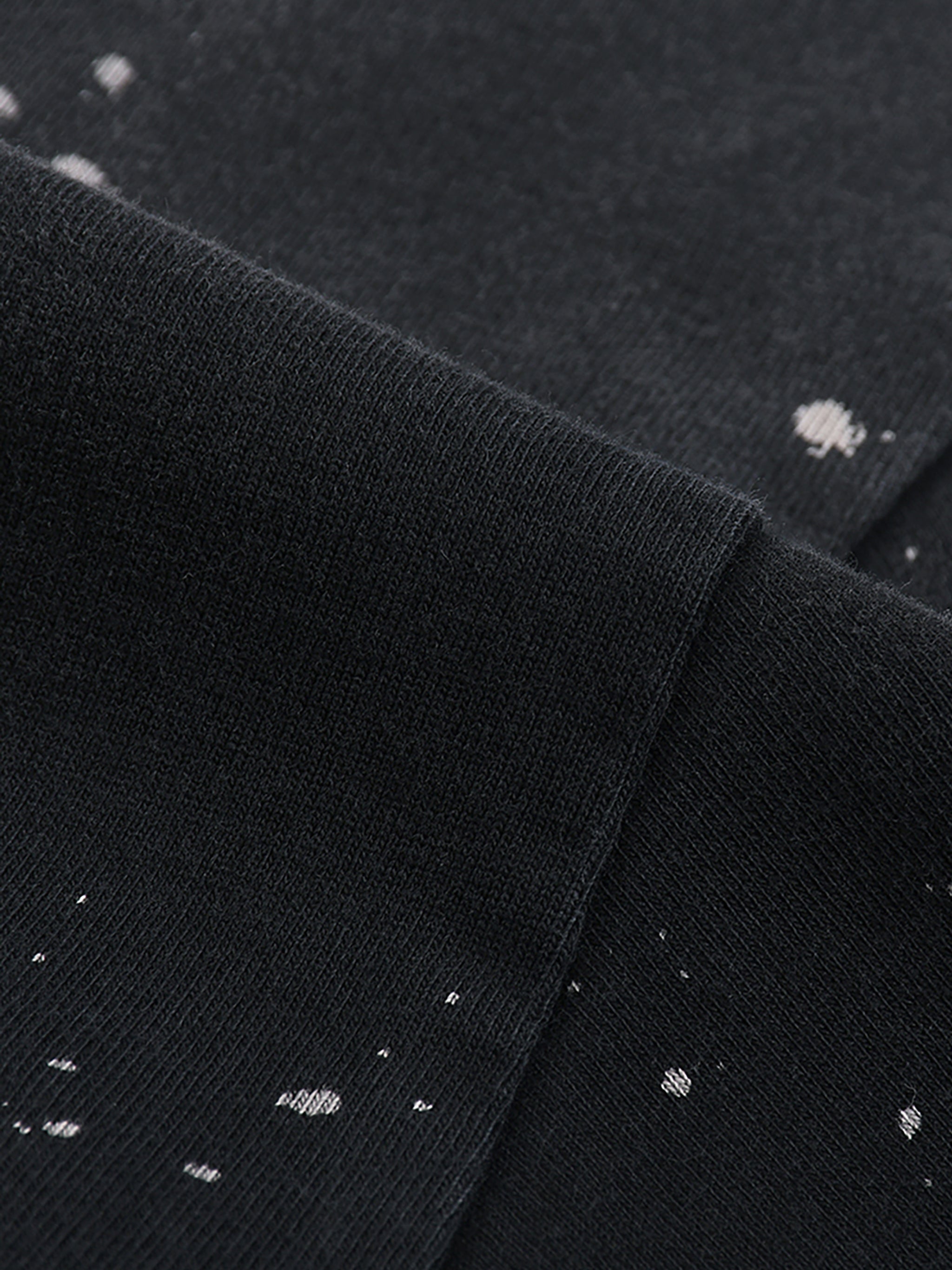 Close-up of black fabric with white speckles, possibly a shirt or sweater.