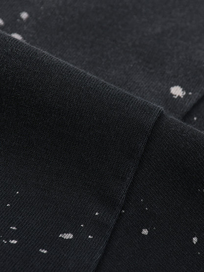 Close-up of black fabric with white speckles, possibly a shirt or sweater.