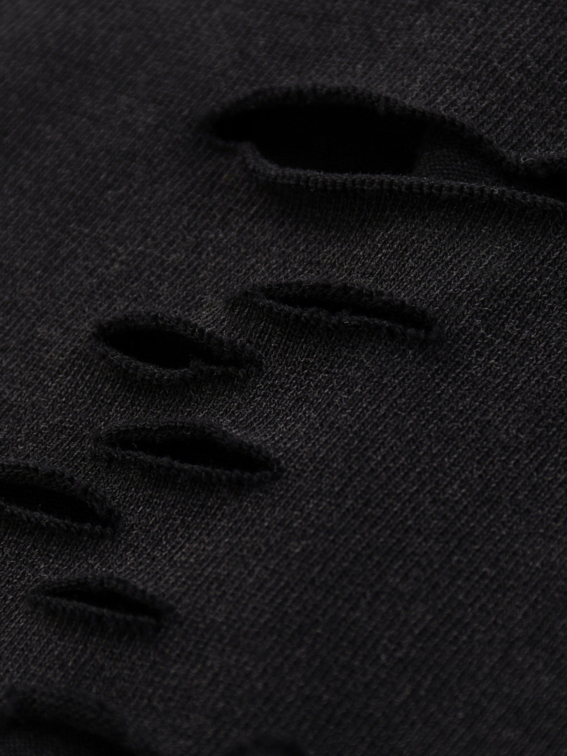 Close-up of black distressed denim fabric
