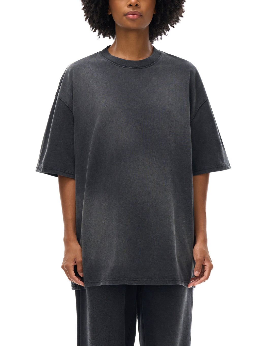 Person wearing a dark gray oversized t-shirt on a white background