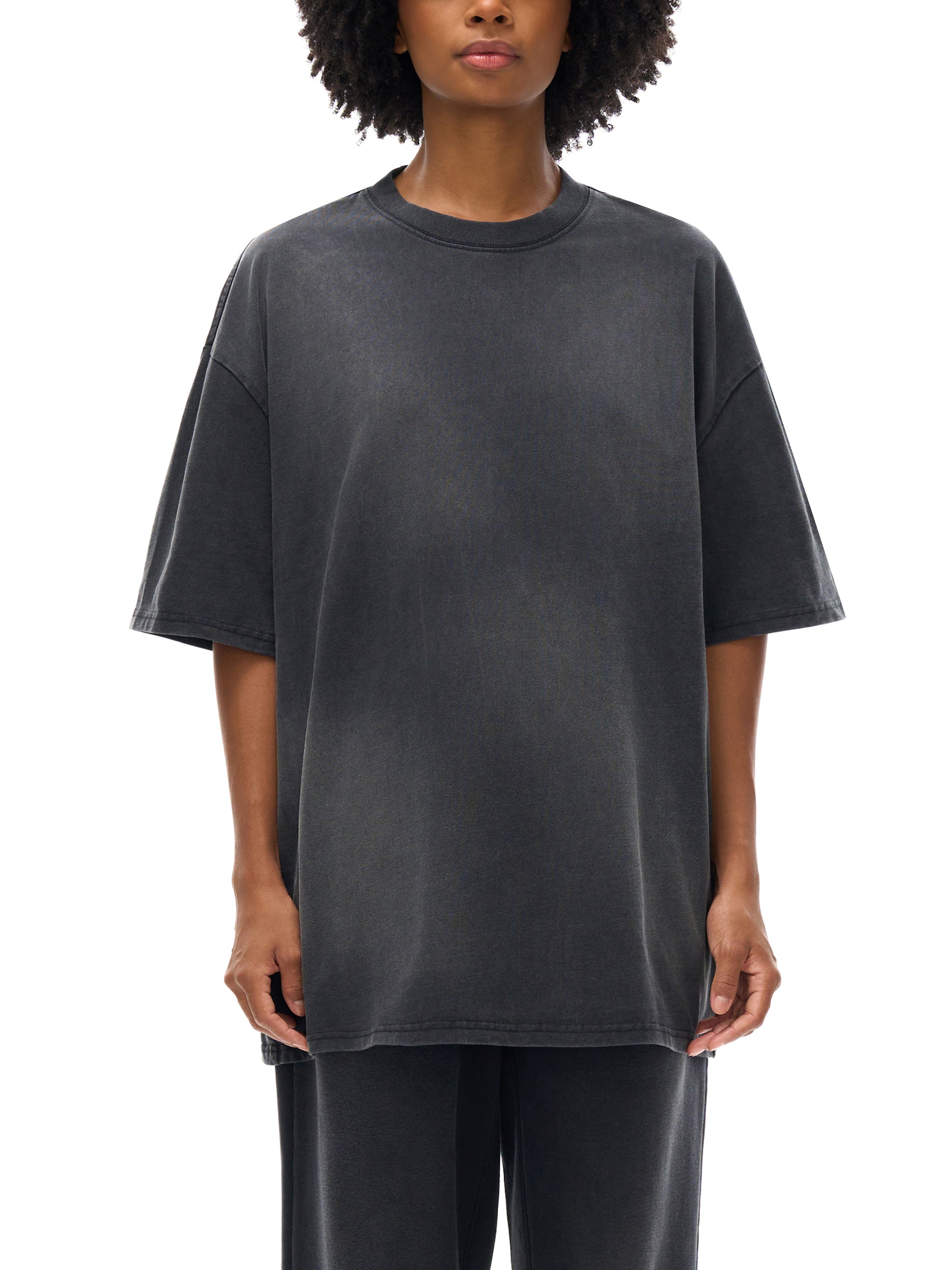 Person wearing a dark gray oversized t-shirt on a white background