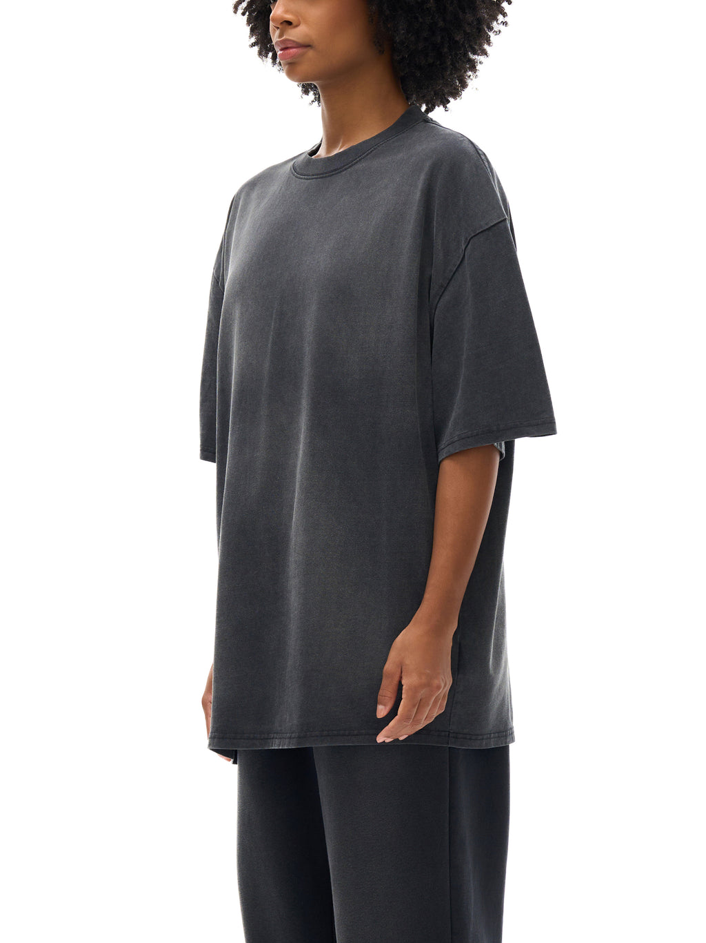Person wearing a dark gray oversized t-shirt on a white background