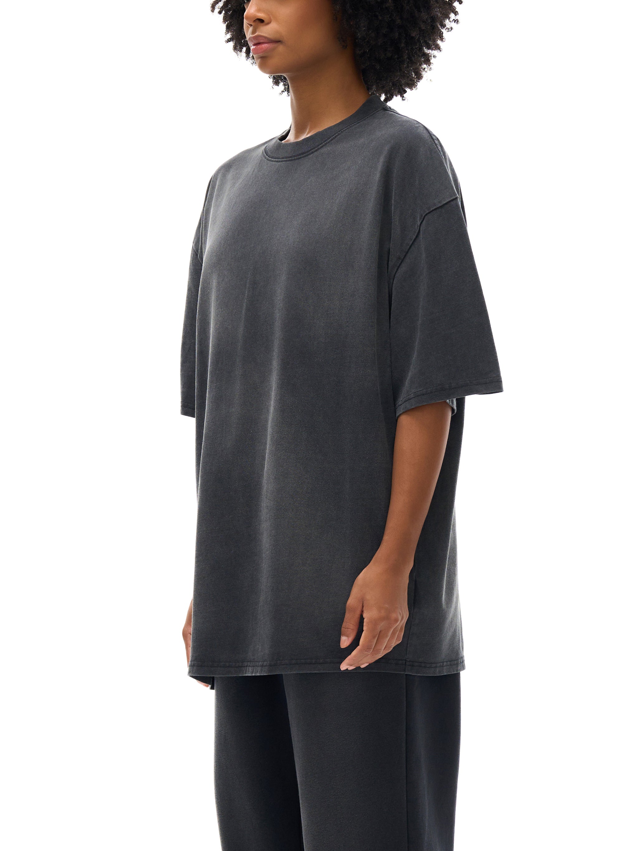 Person wearing a dark gray oversized t-shirt on a white background