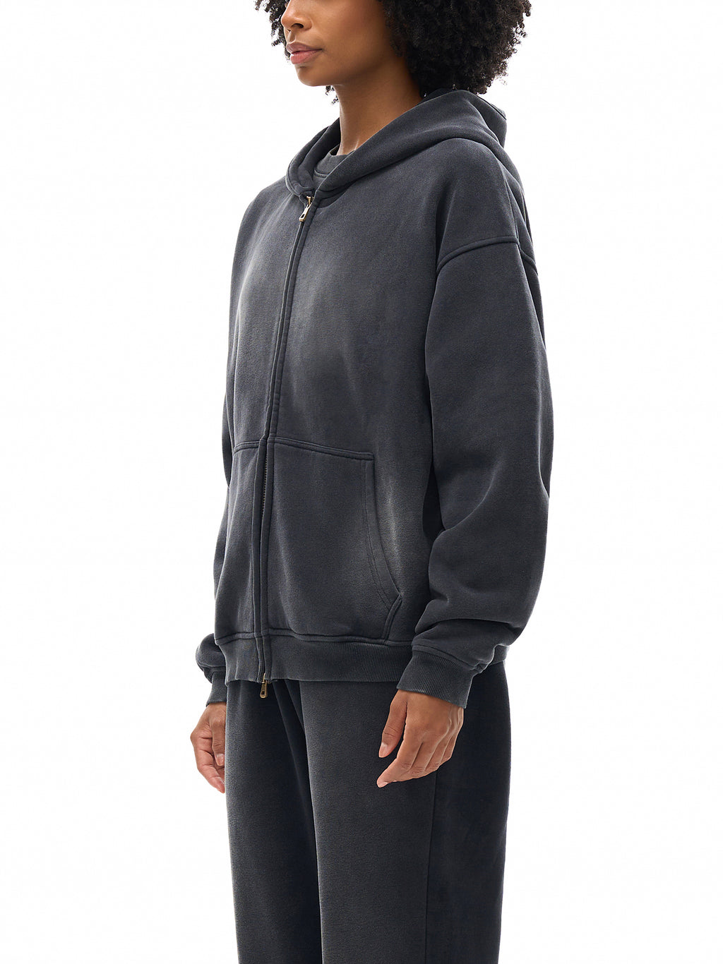 Person wearing a dark gray hoodie and pants on a white background