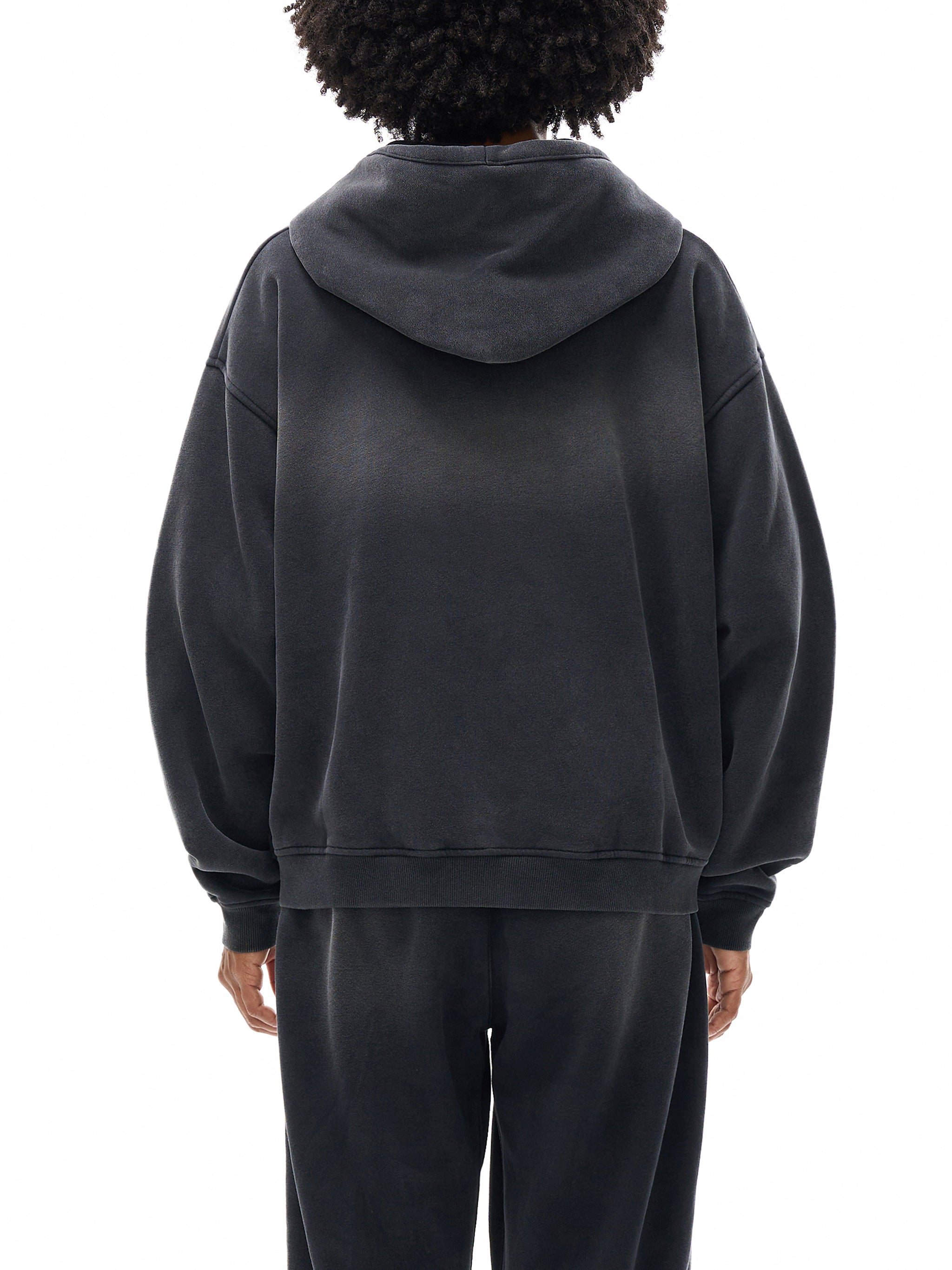 Person wearing a black hoodie and pants on a white background