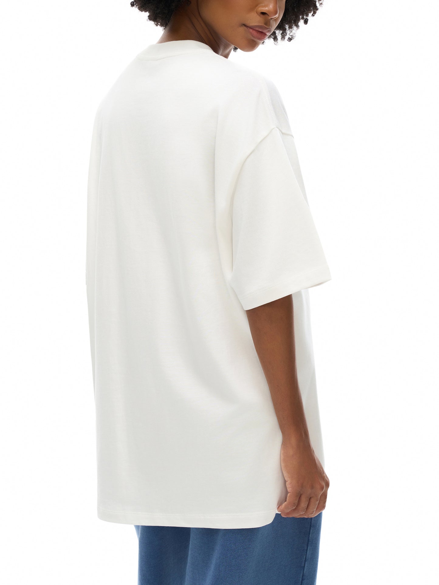 Person wearing a white oversized t-shirt on a white background