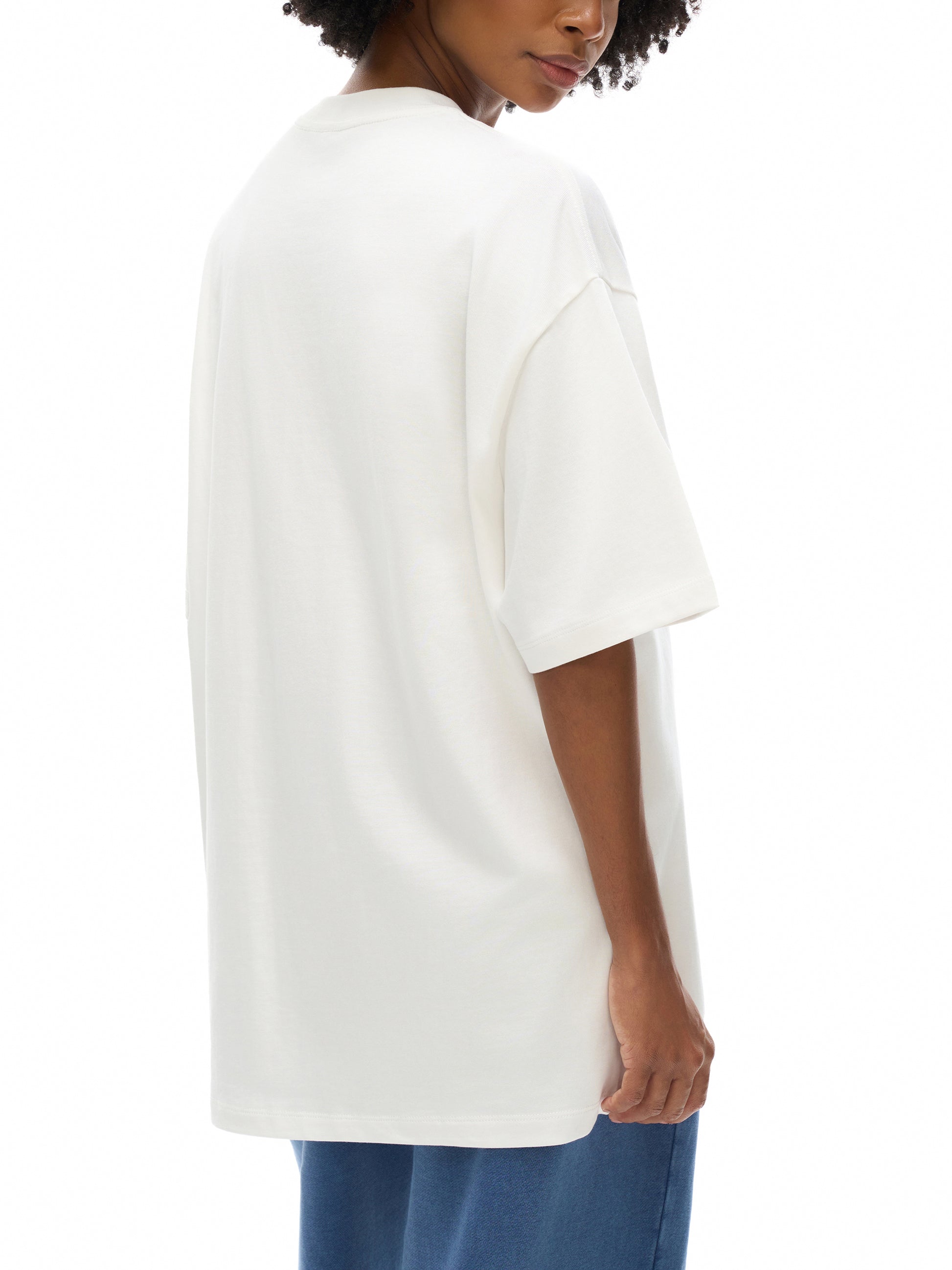 Person wearing a white oversized t-shirt on a white background
