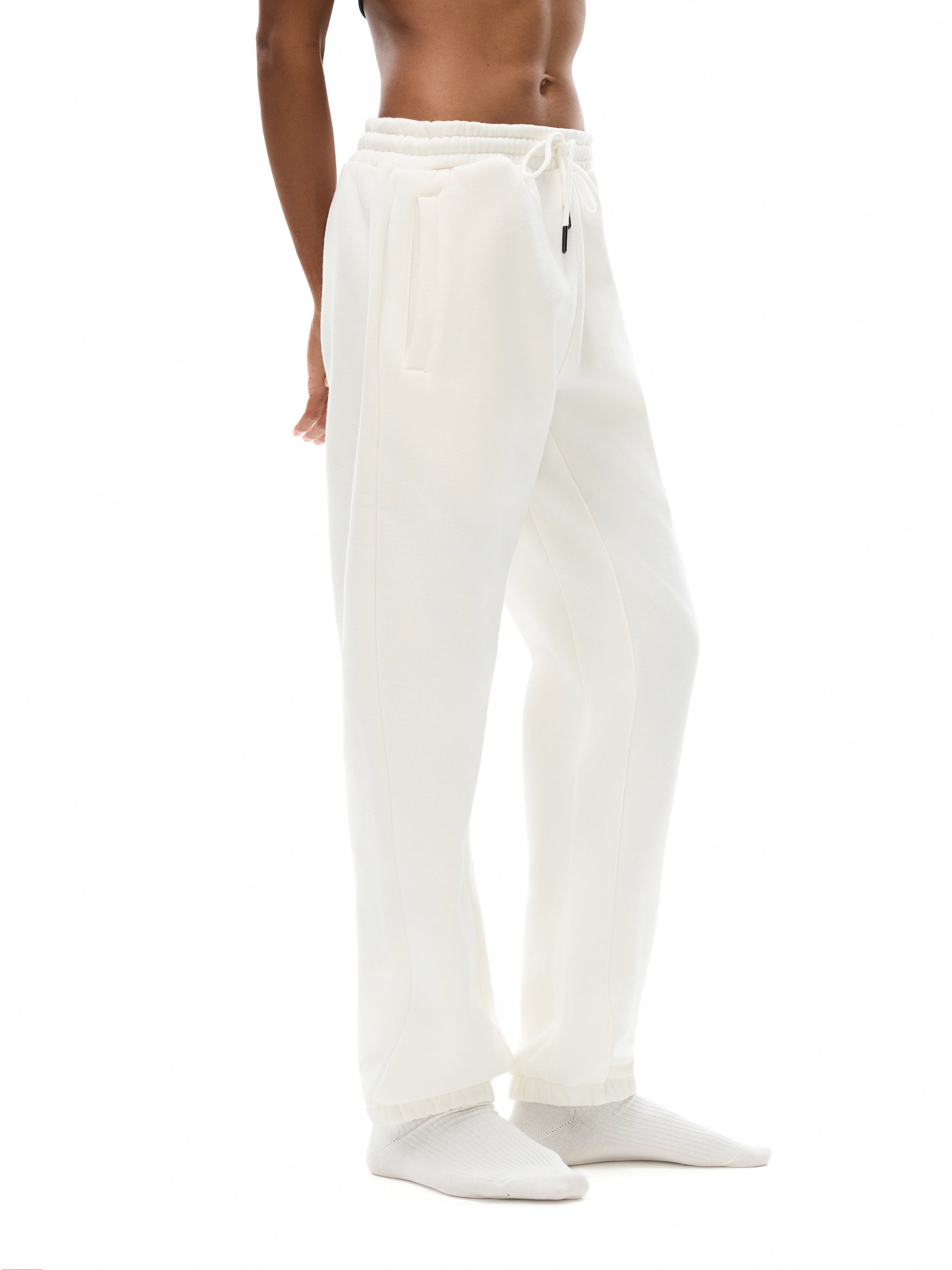 White sweatpants worn by a person on a white background