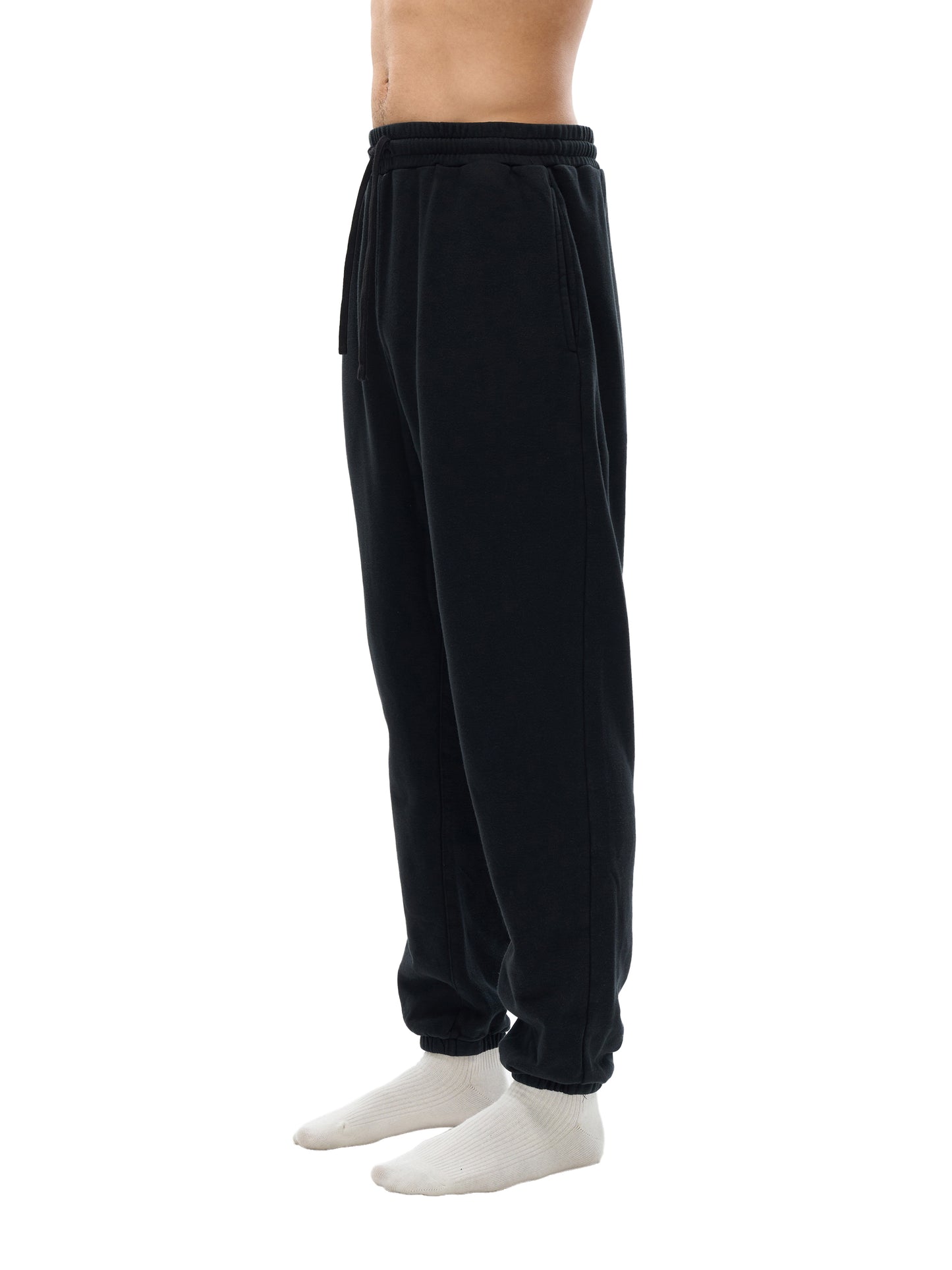 Black sweatpants worn by a person on a white background