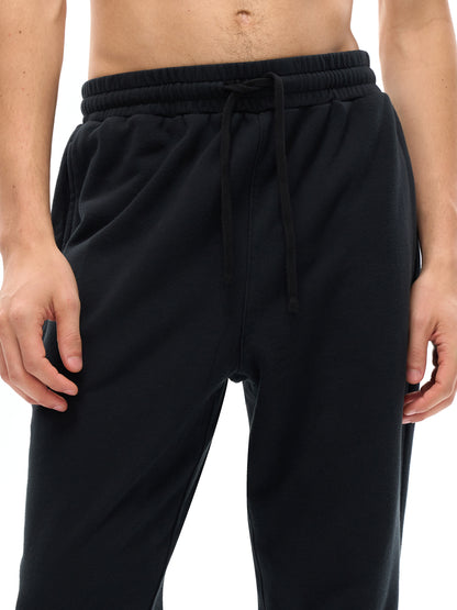 Black jogger pants worn by a person on a white background