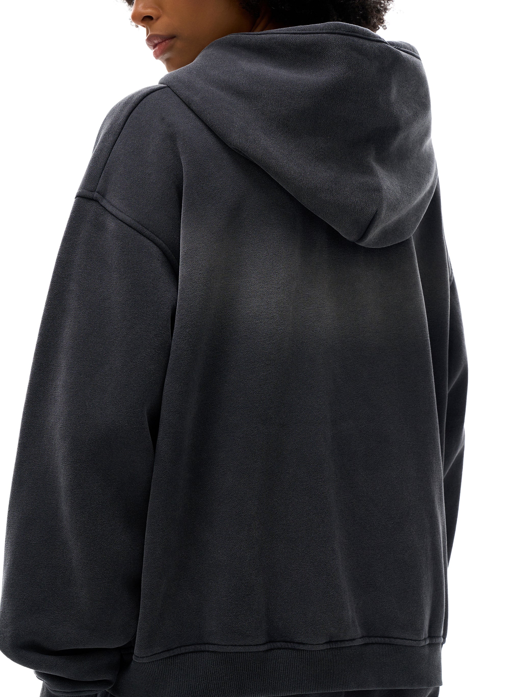 Person wearing a black hoodie from behind on a white background