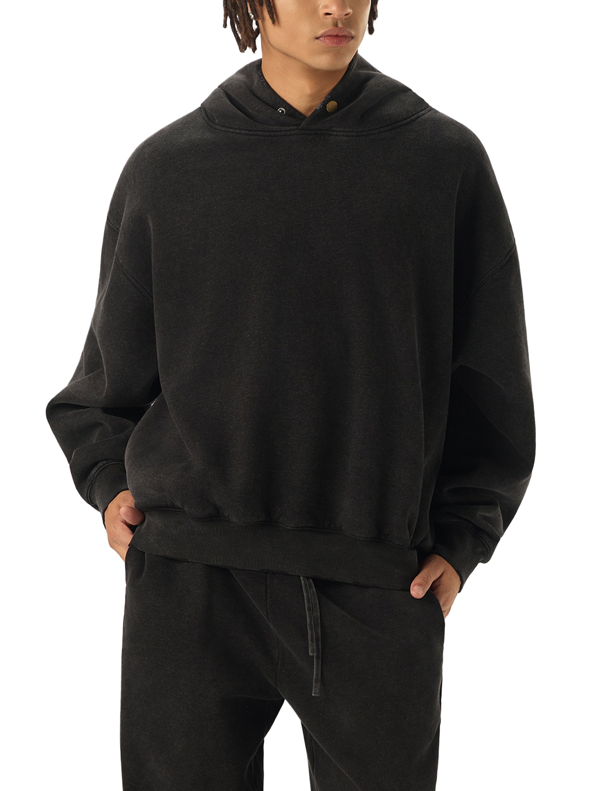 Person wearing a black hoodie and pants on a white background