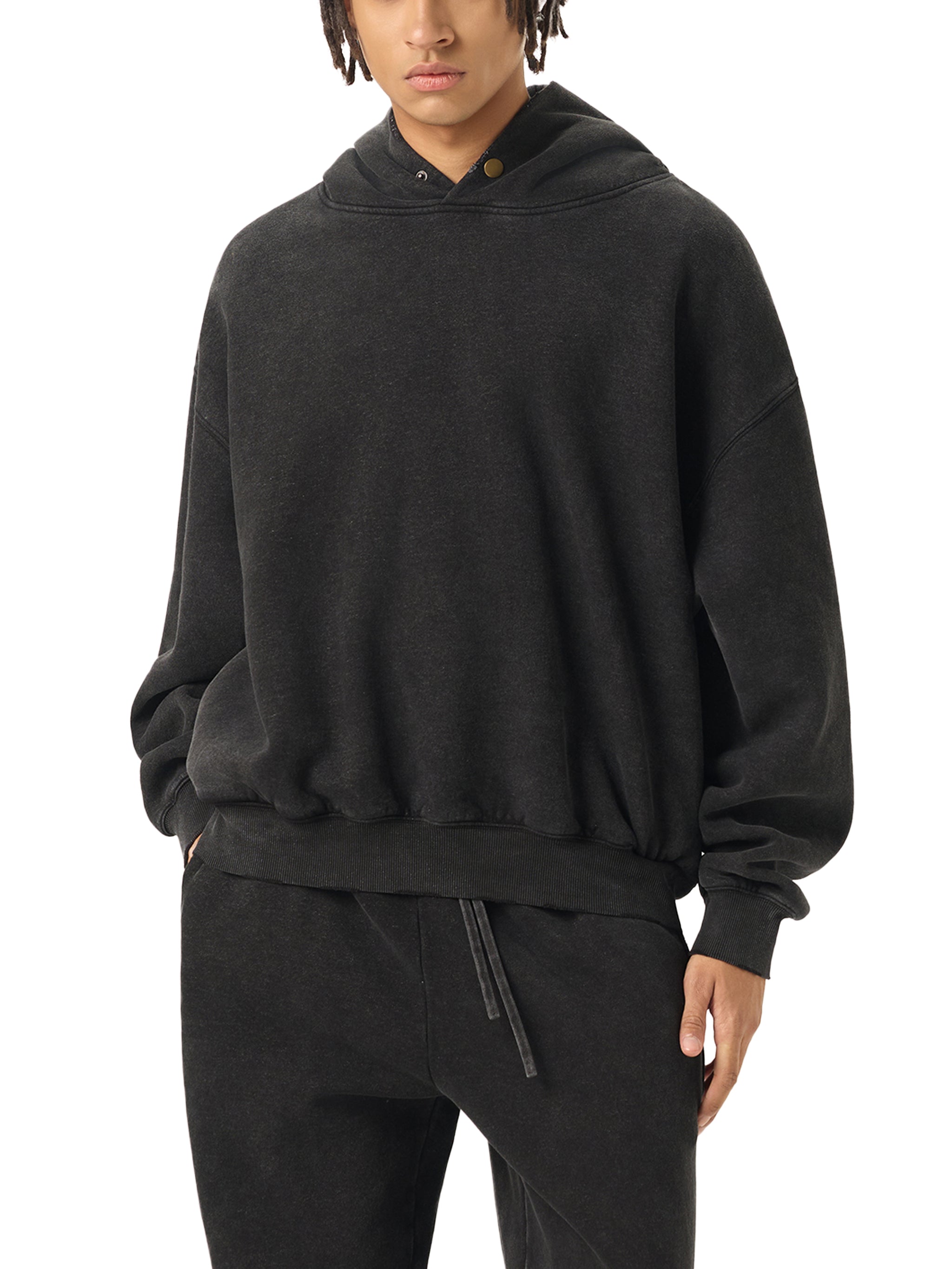 Person wearing a black hoodie and pants on a white background