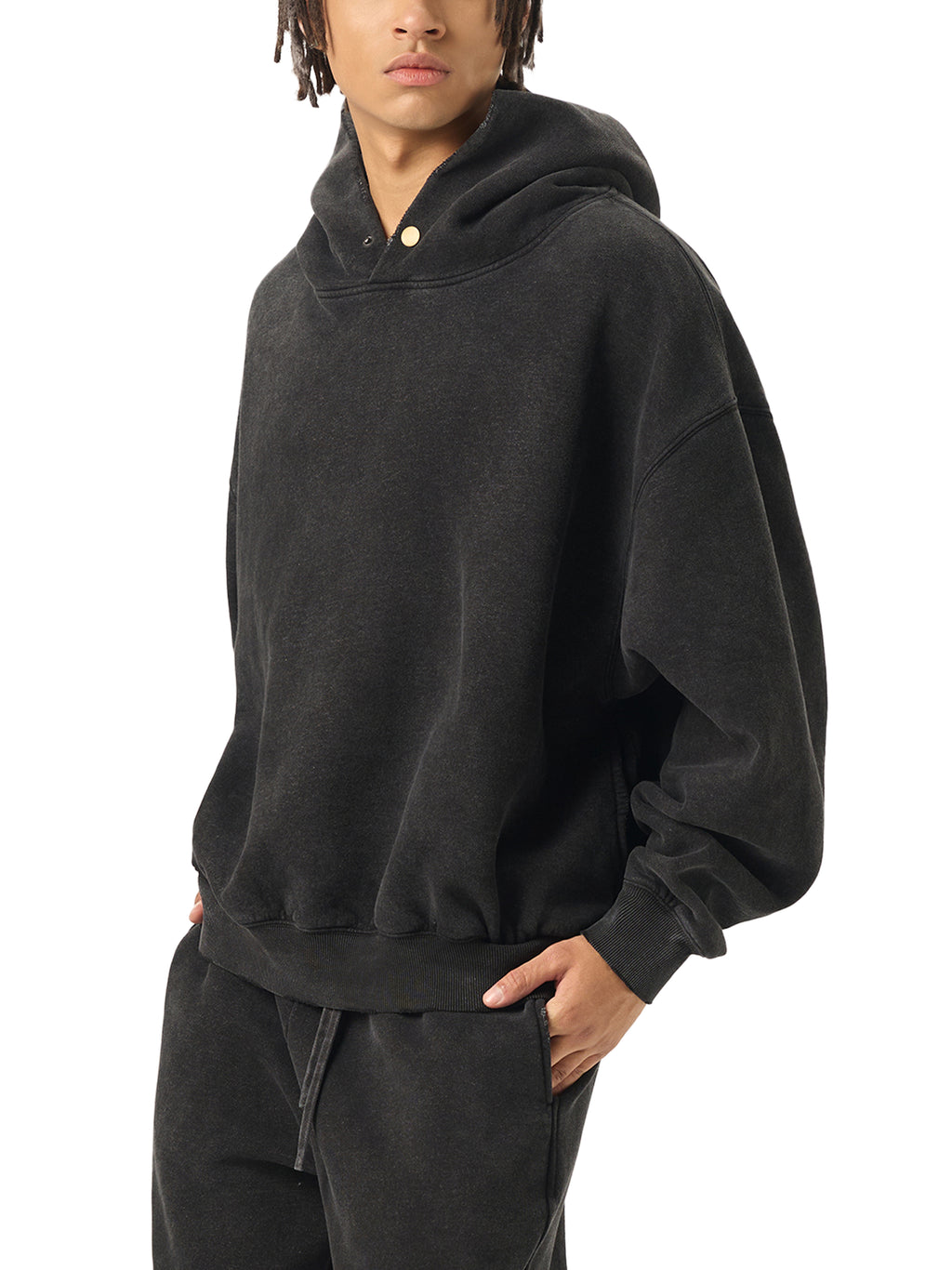 Person wearing a black hoodie and pants on a white background